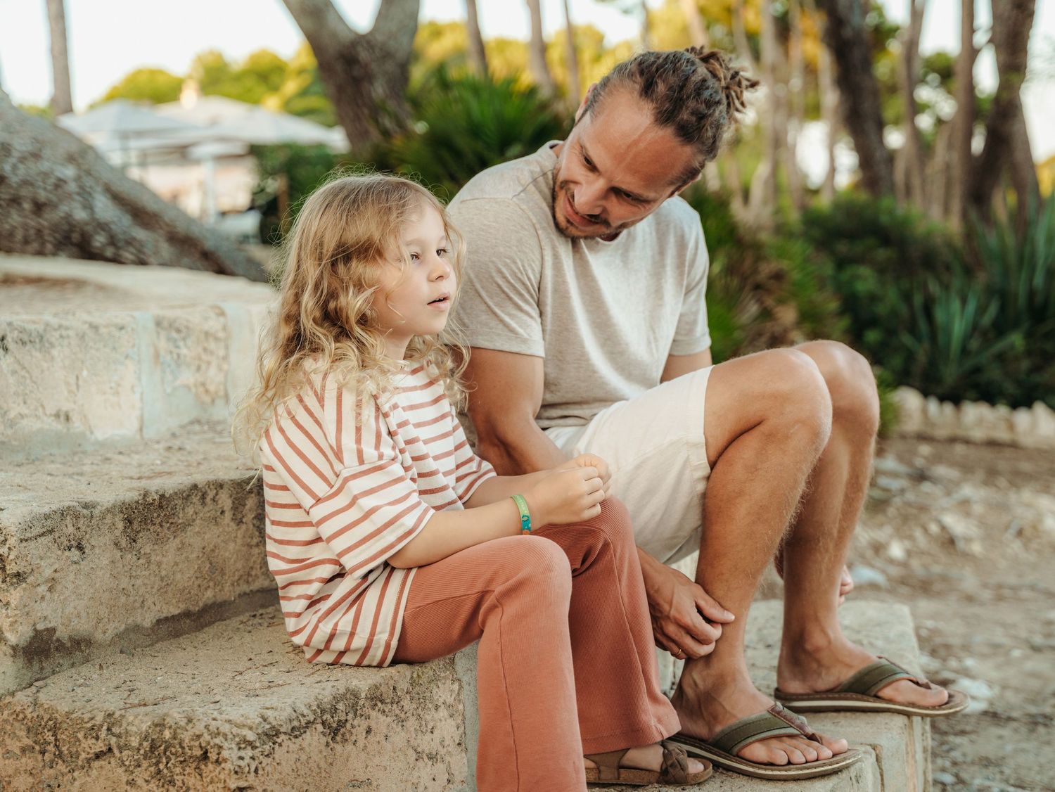 Father and young daughter sitting together on stone steps outdoors.