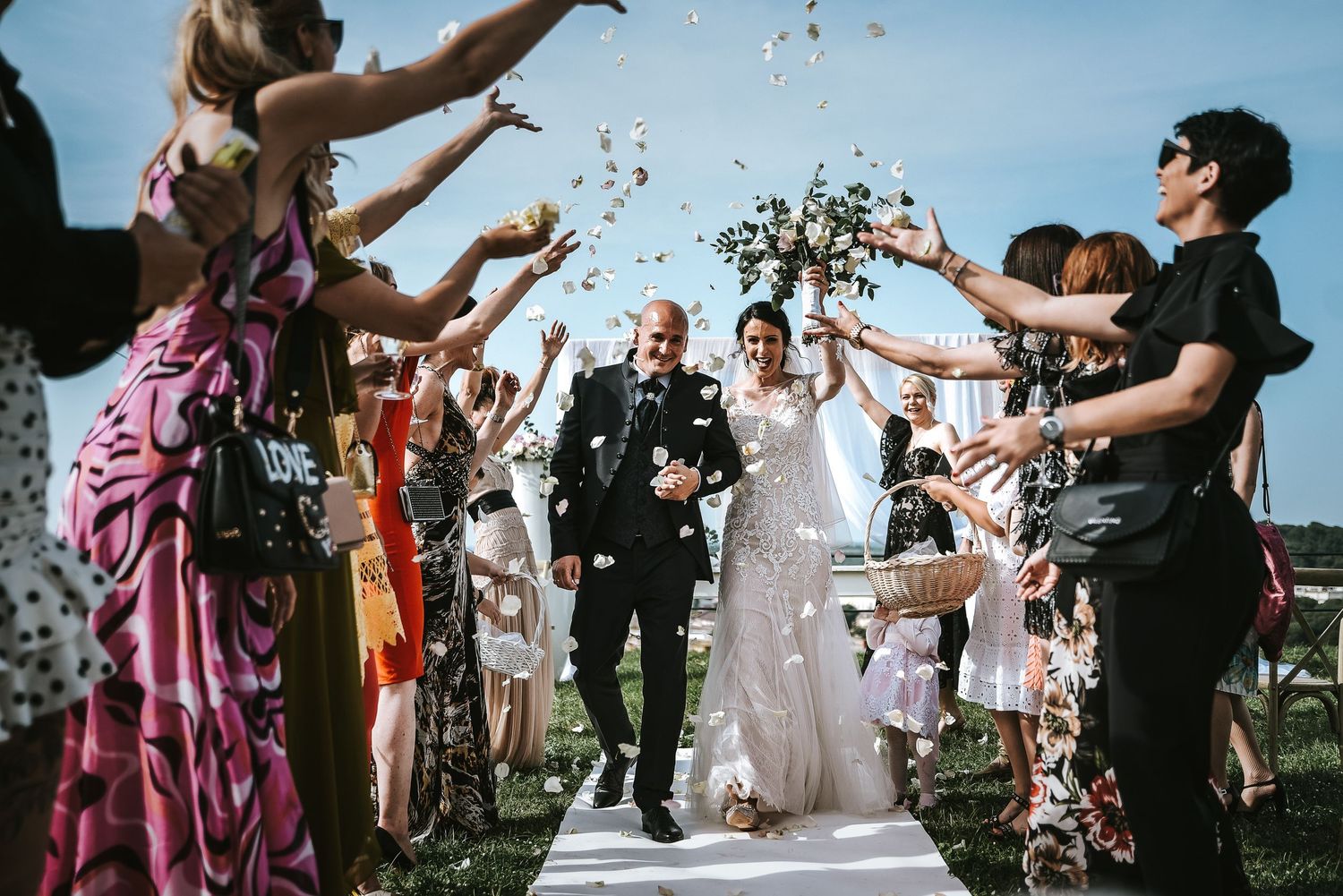 Newlyweds walk through a joyful shower of petals, surrounded by family and friends - wedding photography by Herzenshaus Studio, Frankfurt.