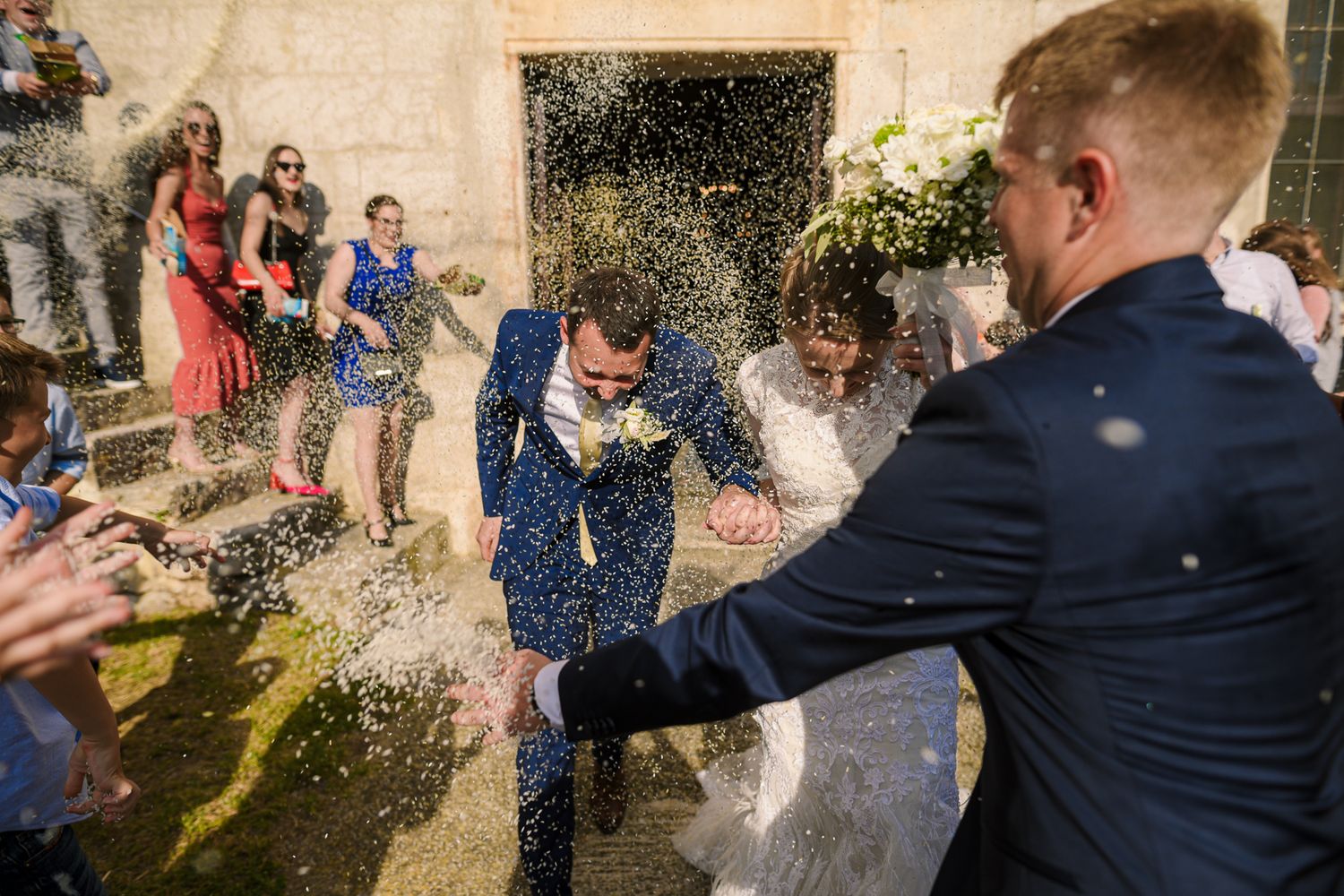 Bride and groom showered with confetti by joyful guests outside the church after their ceremony.