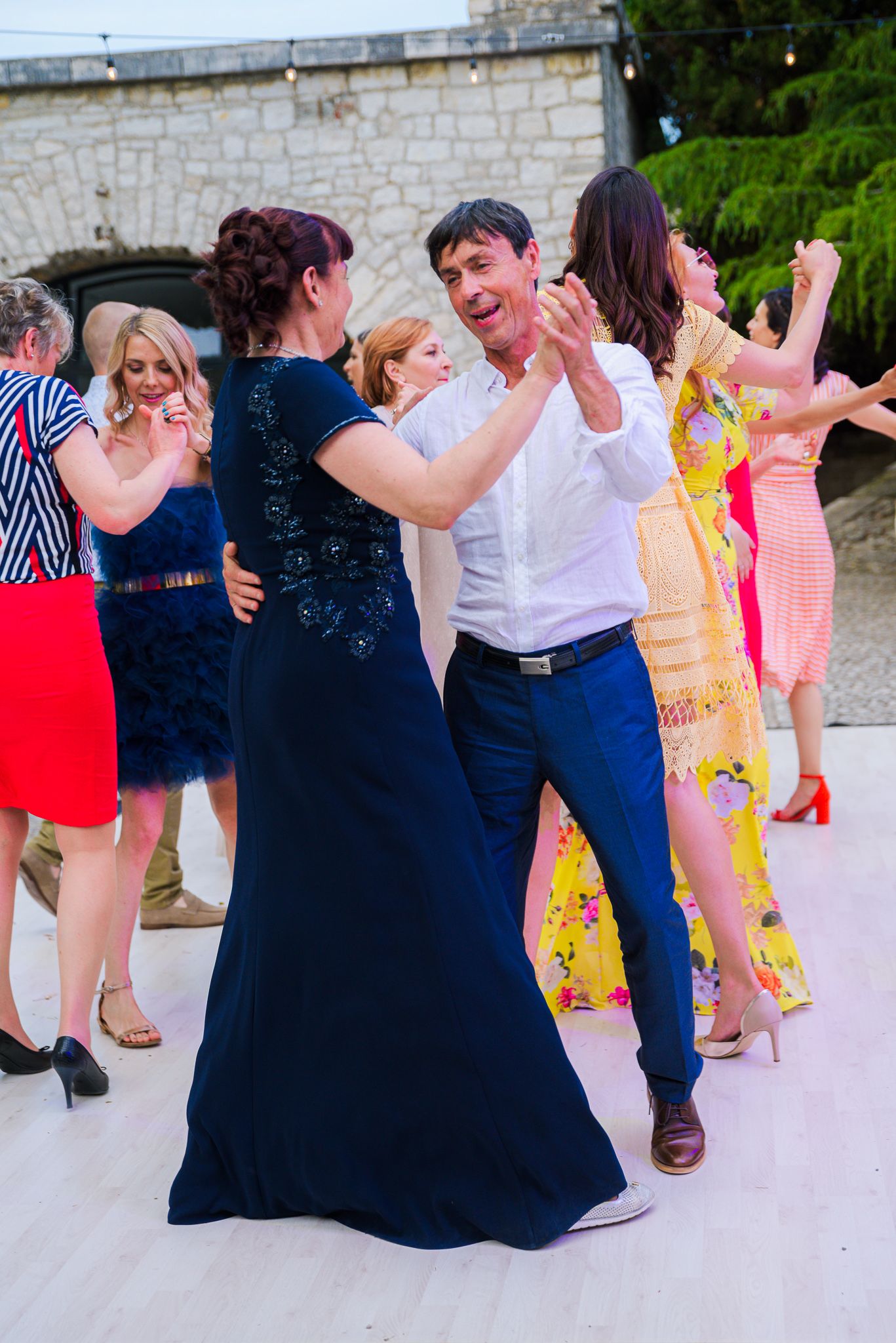 Couple dancing together at a wedding reception while guests enjoy the celebration around them.
