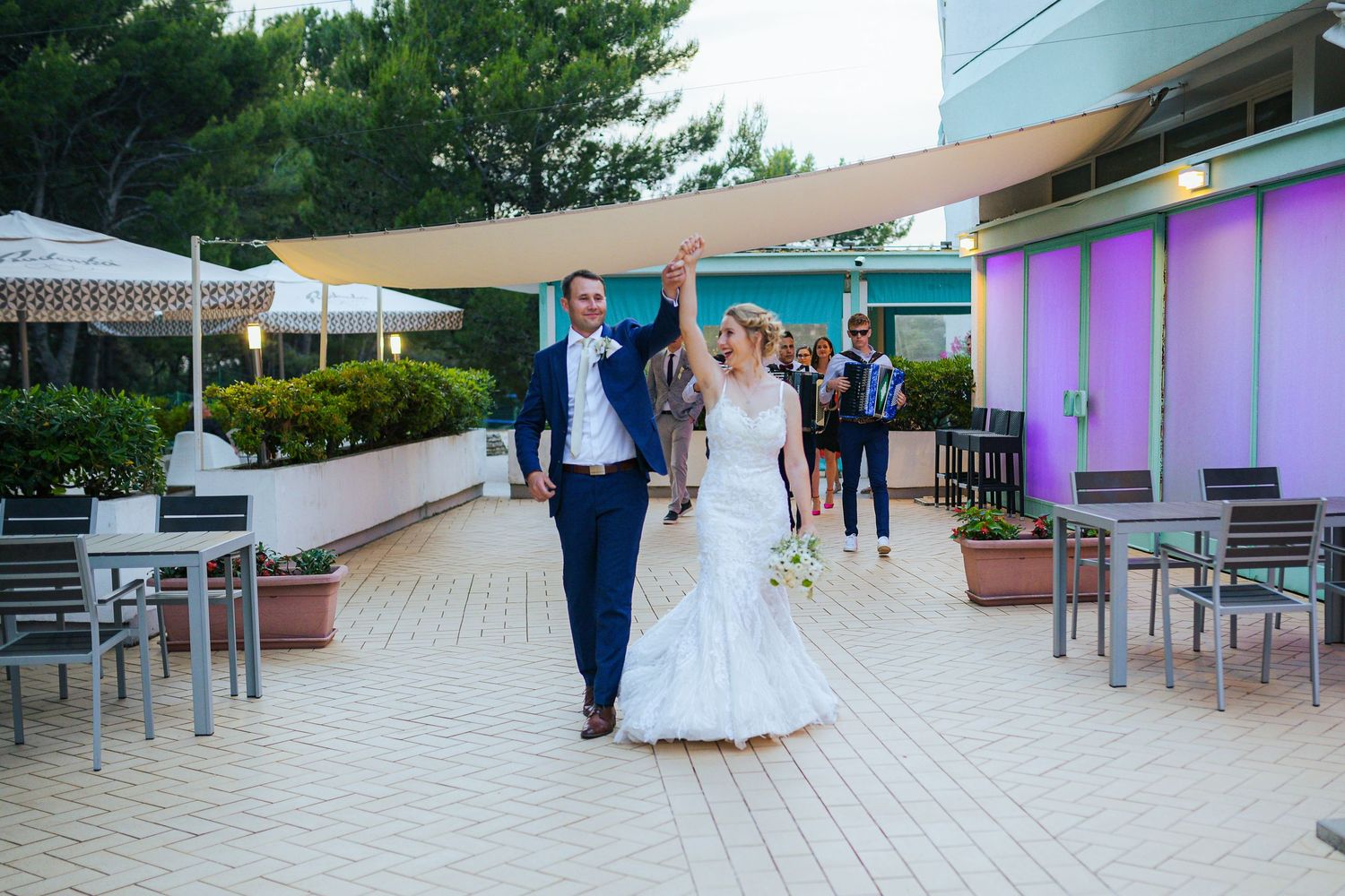 Happy newlyweds walking hand in hand at an outdoor wedding reception venue.