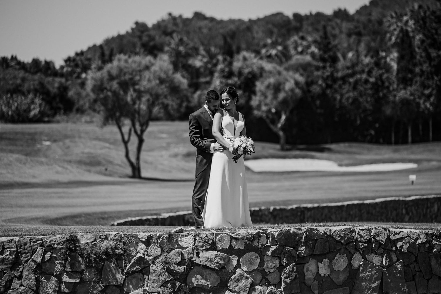 Black and white wedding portrait of a bride and groom ebracing outdoors in a scenic countryside setting. Herzenshaus Studio, Frankfurt.