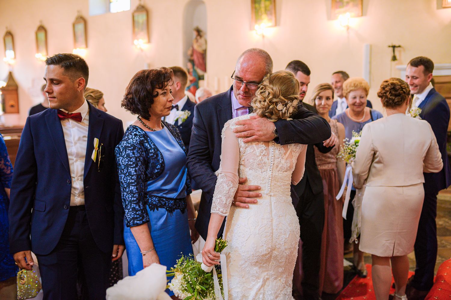 Bride embraces a family member warmly inside the church surrounded by wedding guests.