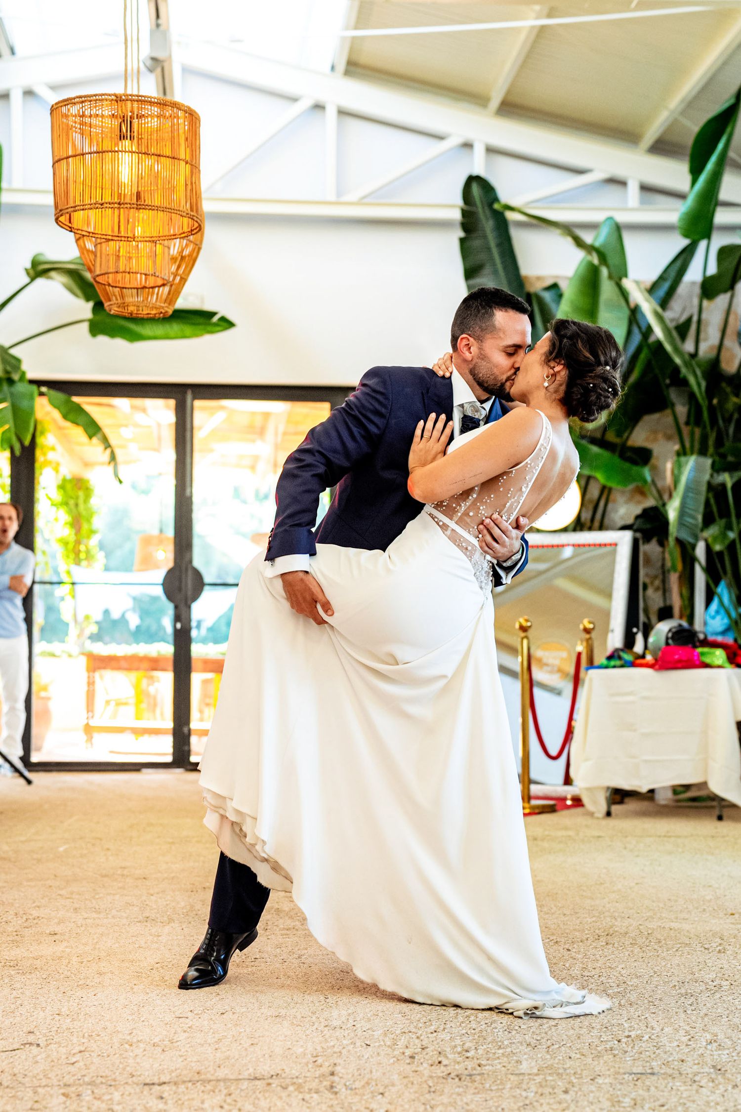 Groom lifts bride for a romantic kiss during their first dance at an elegant wedding reception venue.