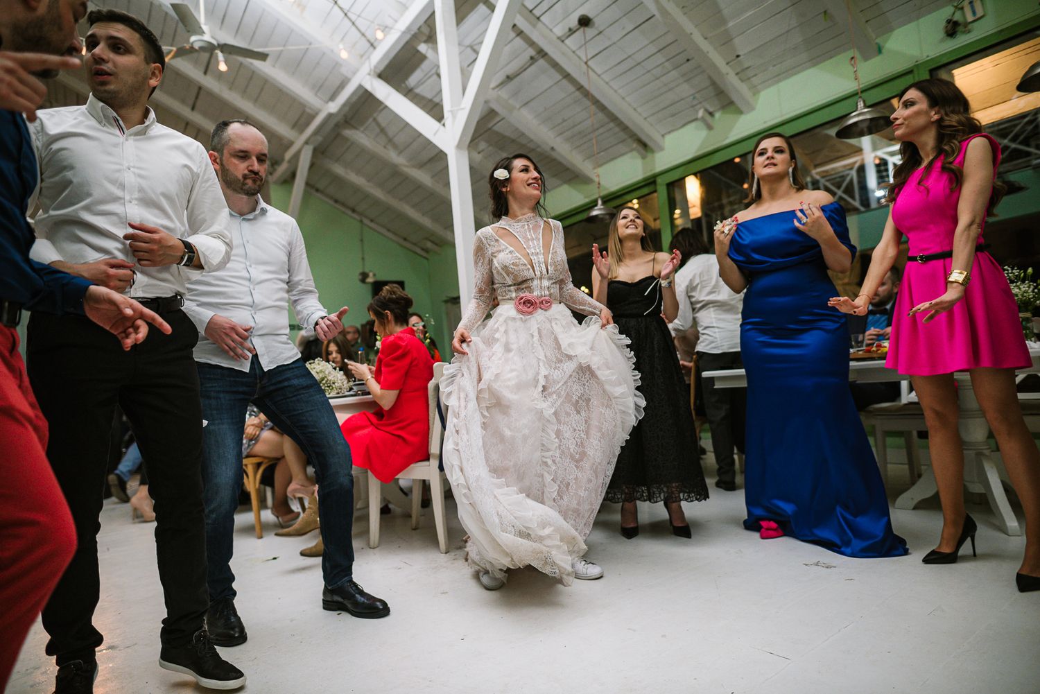 Bride in lace gown dances gracefully with guests at vibrant wedding reception party.
