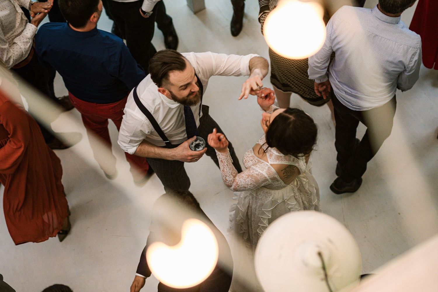 Aerial view of bride and groom dancing together under bright lights at wedding reception.