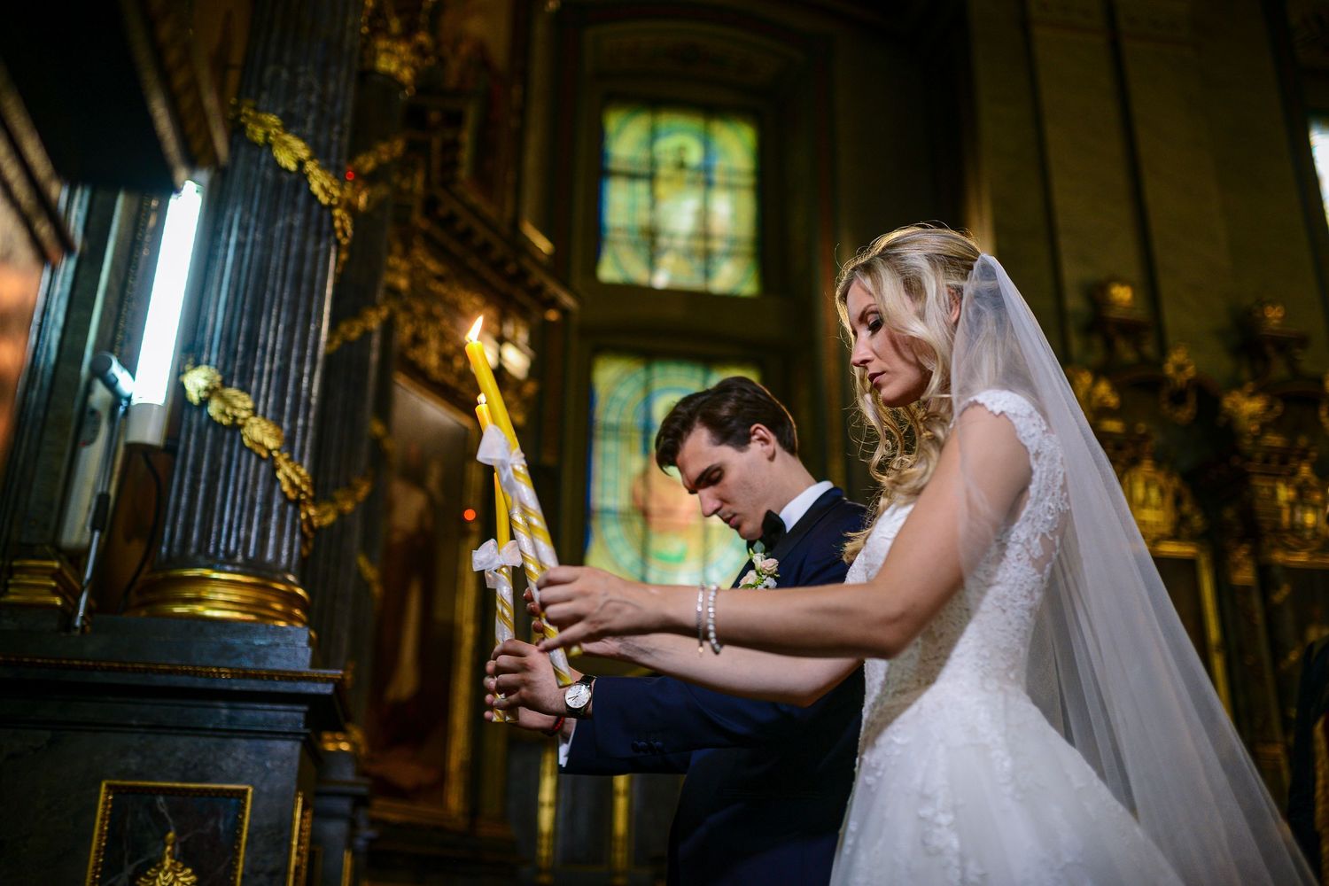 Bride and groom lighting candles together during a traditional church wedding ceremony.