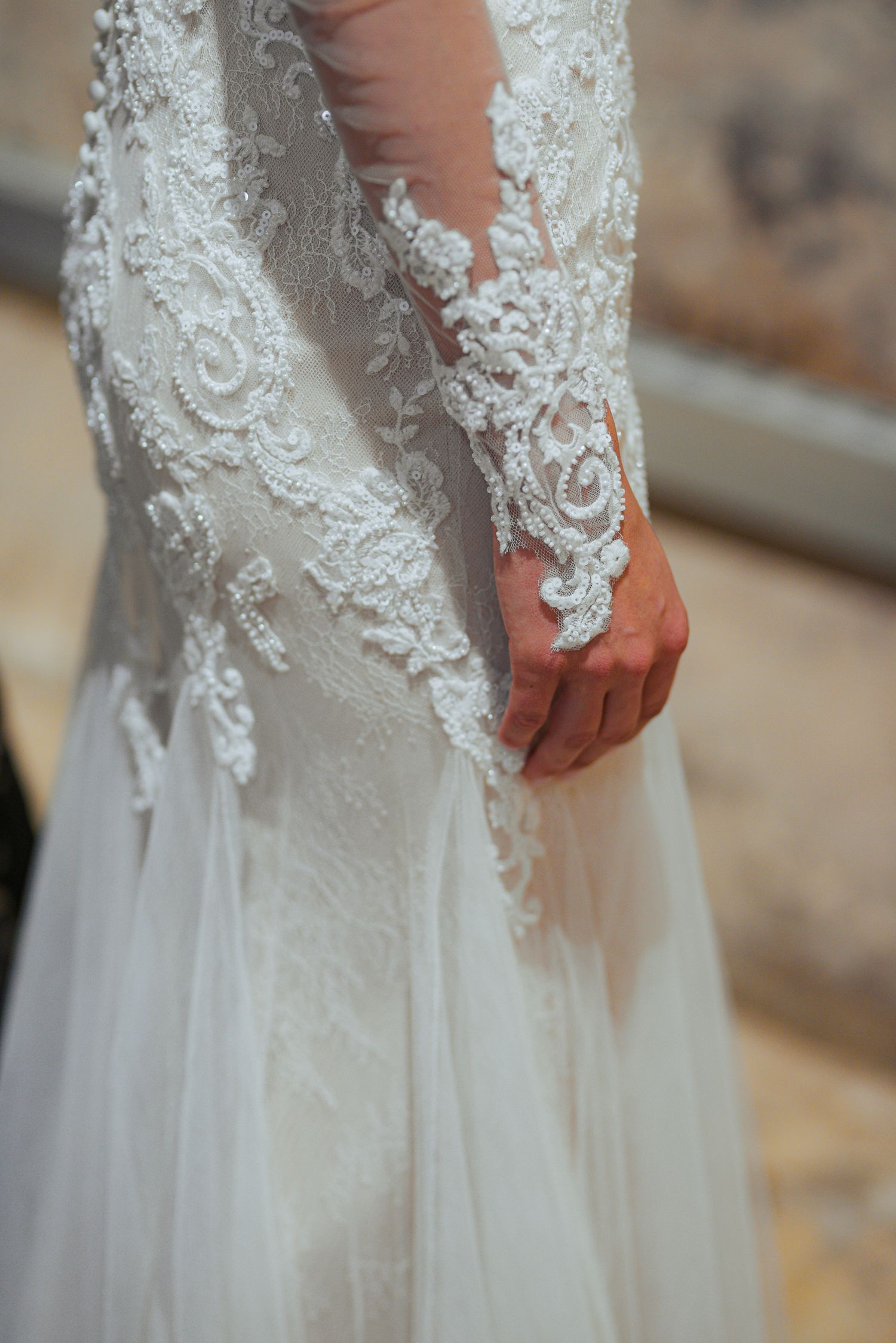Close-up of intricate floral lace detailing on a long-sleeve bridal gown.