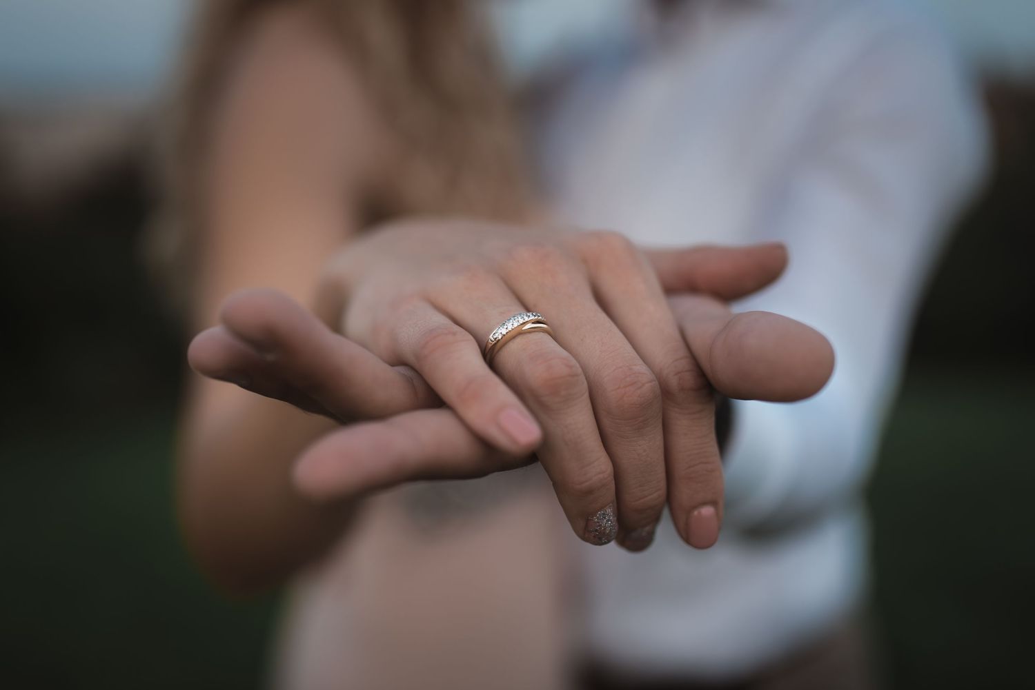Close-up of newlyweds holding hands with wedding rings, capturing an intimate moment during their wedding day. By Herzenshaus Studio.