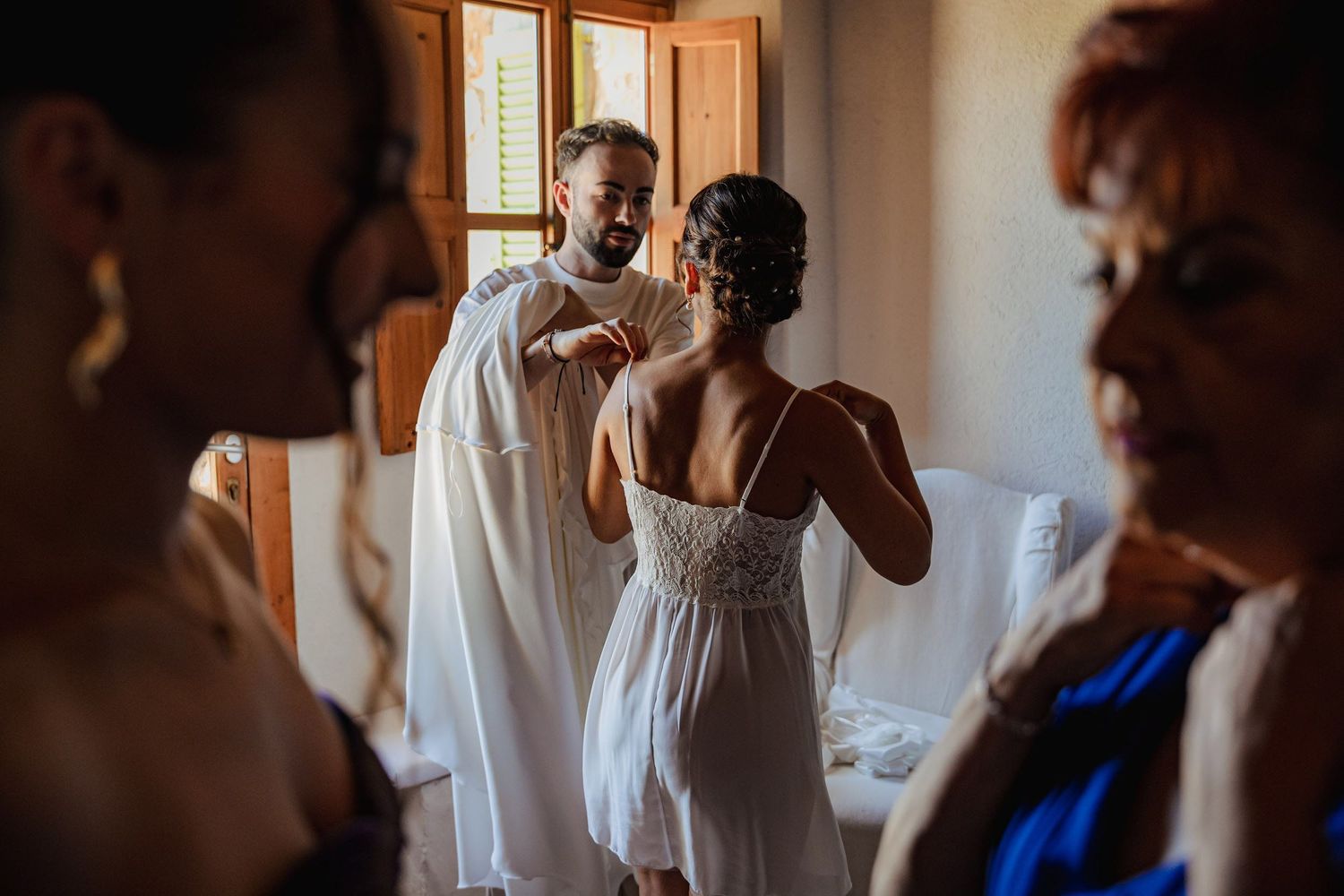 Bride getting ready with friends before the wedding ceremony, captured in warm natural light during bridal preparations. Herzenshaus Studio.