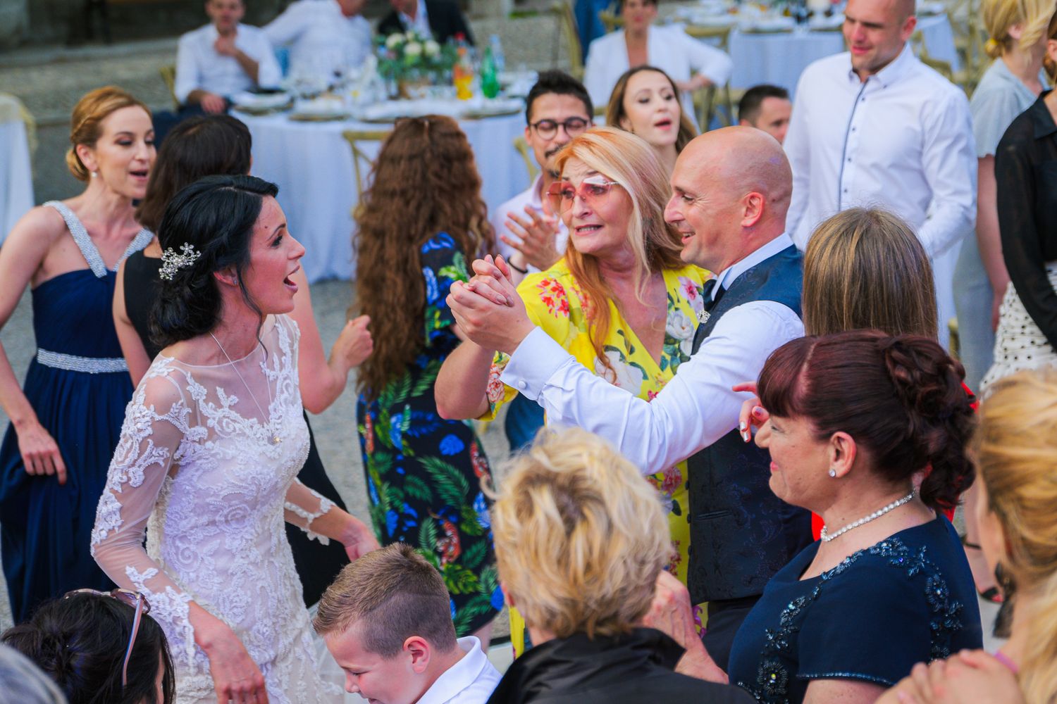 Bride and groom celebrating joyfully with guests on the outdoor wedding reception dance floor.