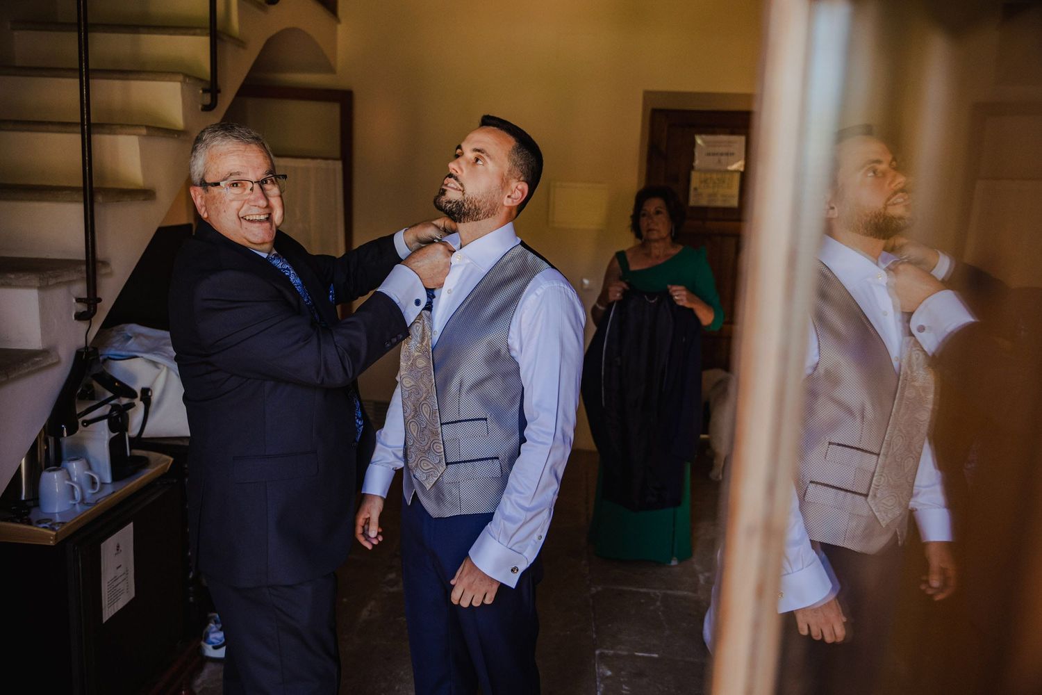 Father helping groom adjust his tie while getting ready for the wedding ceremony.