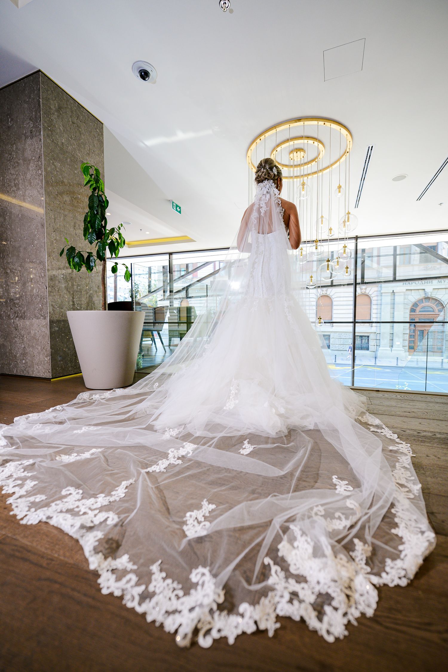 Bride in stunning white lace gown with an elaborate long embroidered veil spread across the floor.