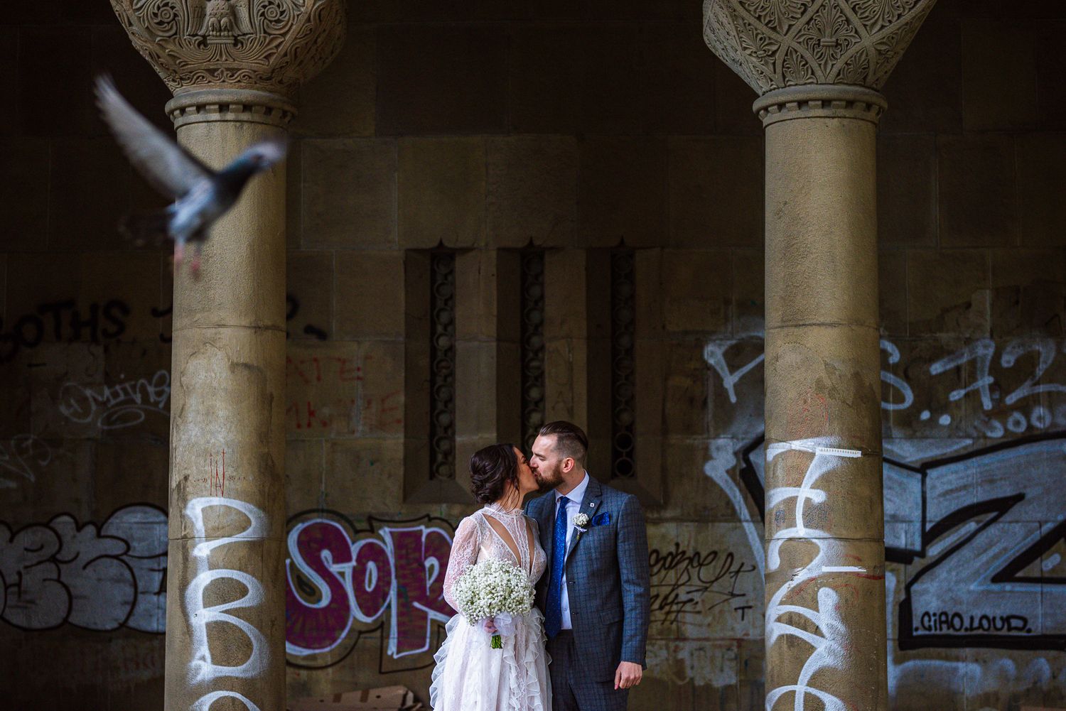 Bride and groom sharing a kiss beneath historic arches, timeless wedding photography by Herzenshaus Studio, Frankfurt Rhein-Main.