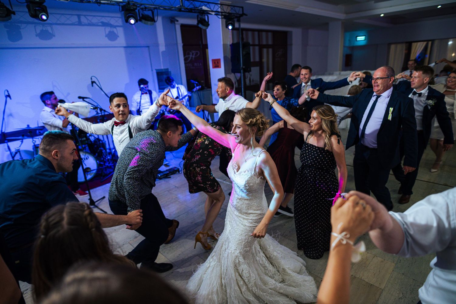 Bride and wedding guests dancing energetically together at a lively wedding party.