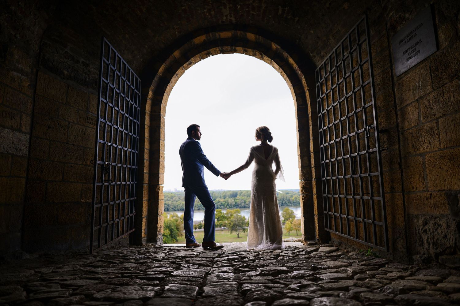 Bride and groom holding hands beneath a historic store archway, photographed by Herzenshaus Studio in Germany