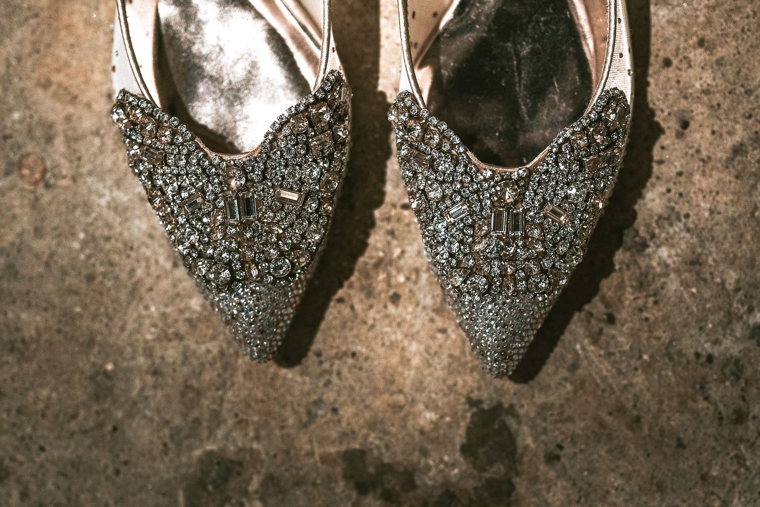 Ornate crystal-embellished pointed-toe wedding flats with intricate beading on stone floor.