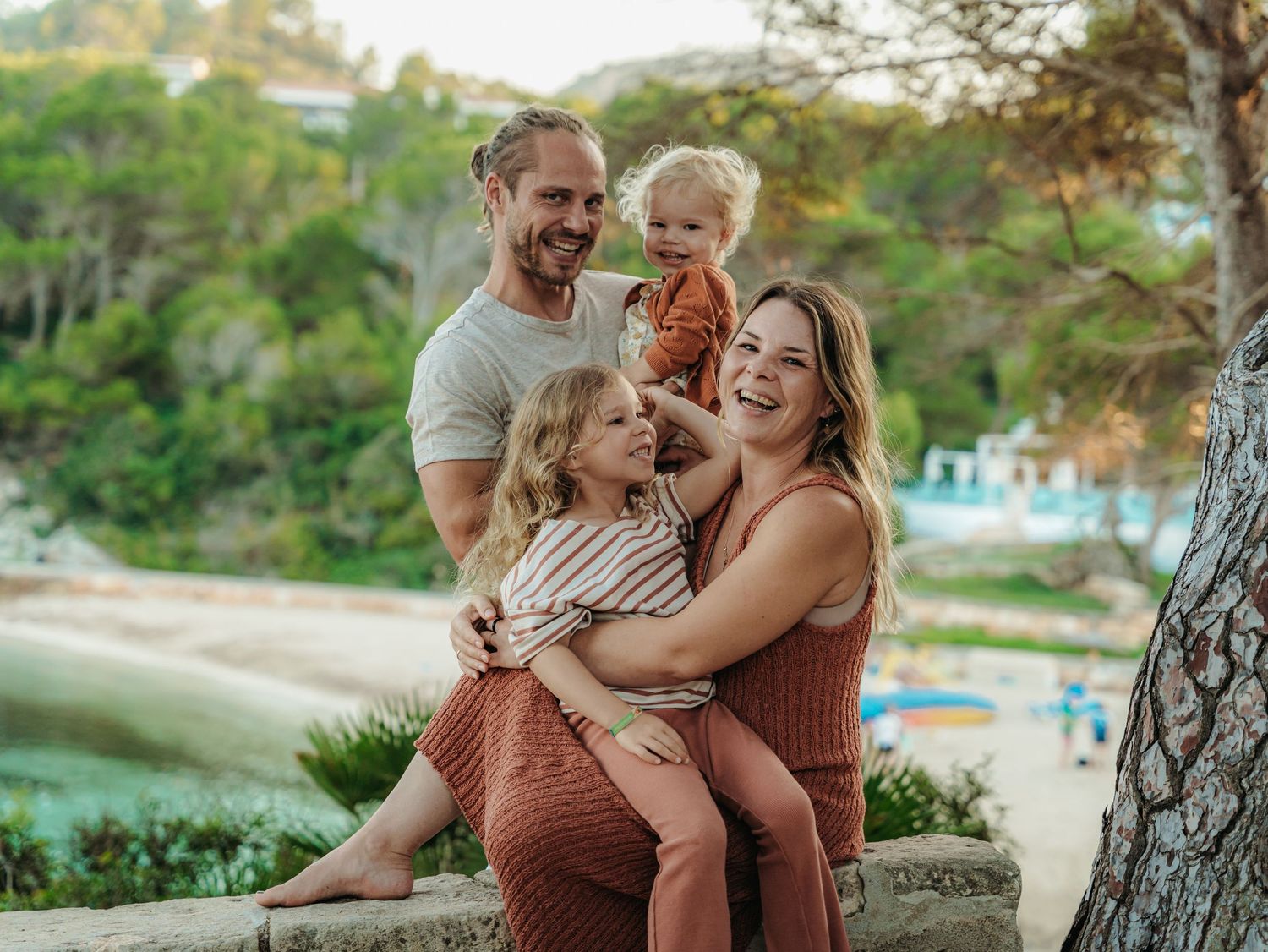 Smiling family with two young children enjoying outdoor photo session by scenic coastal beach.
