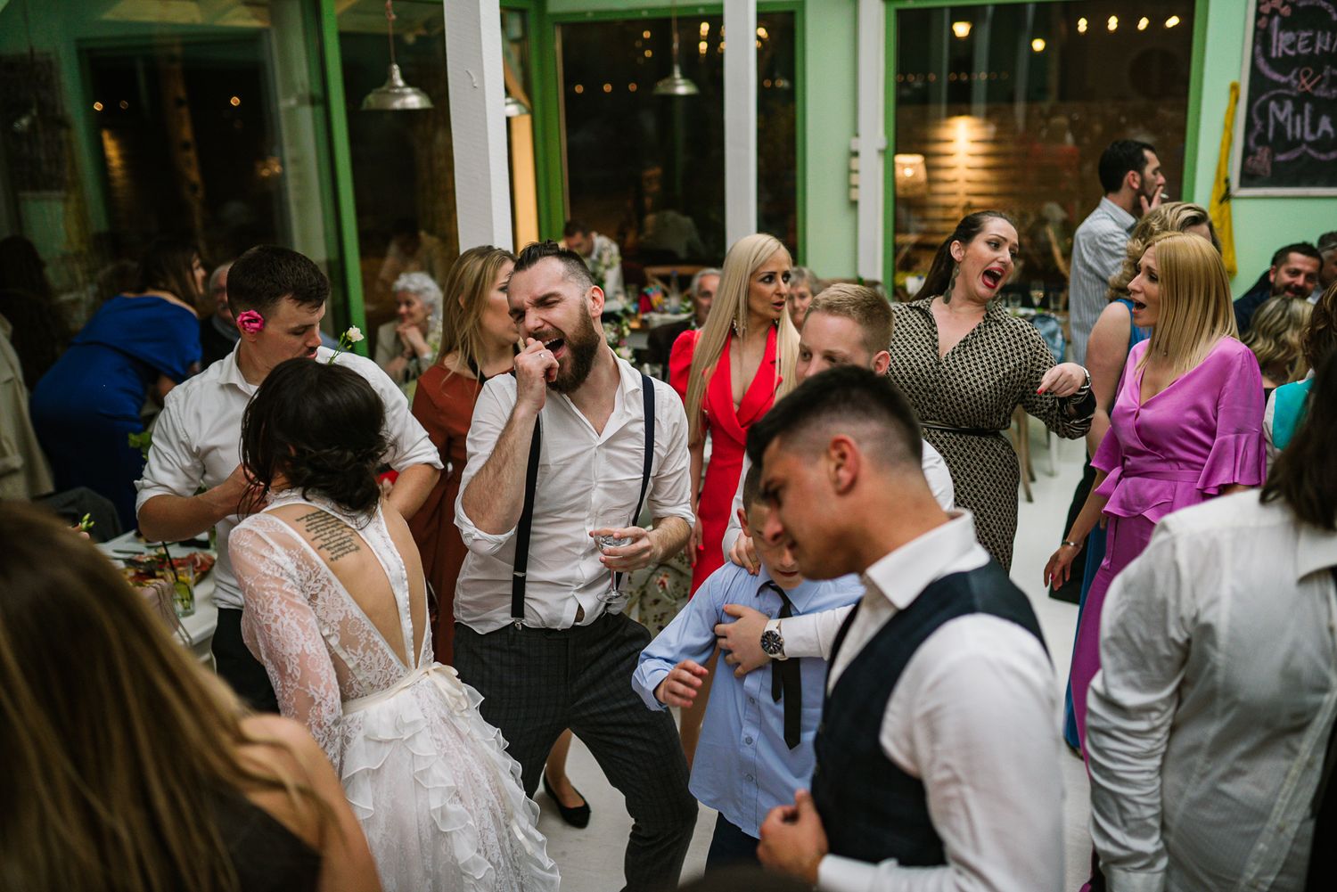 Wedding guests dancing and celebrating joyfully at a lively indoor wedding reception party.