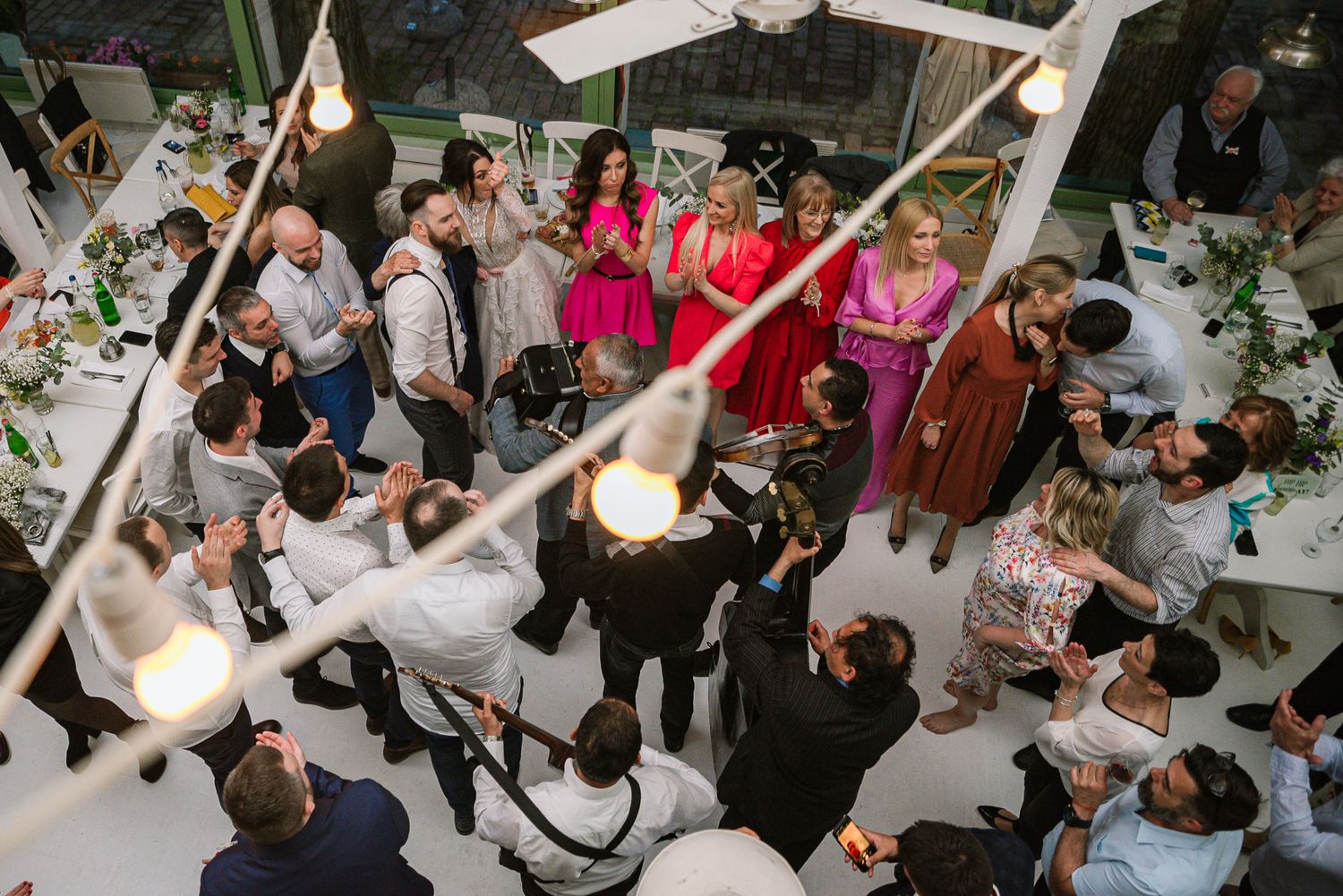 Aerial view of wedding guests dancing and celebrating at a festive indoor reception.