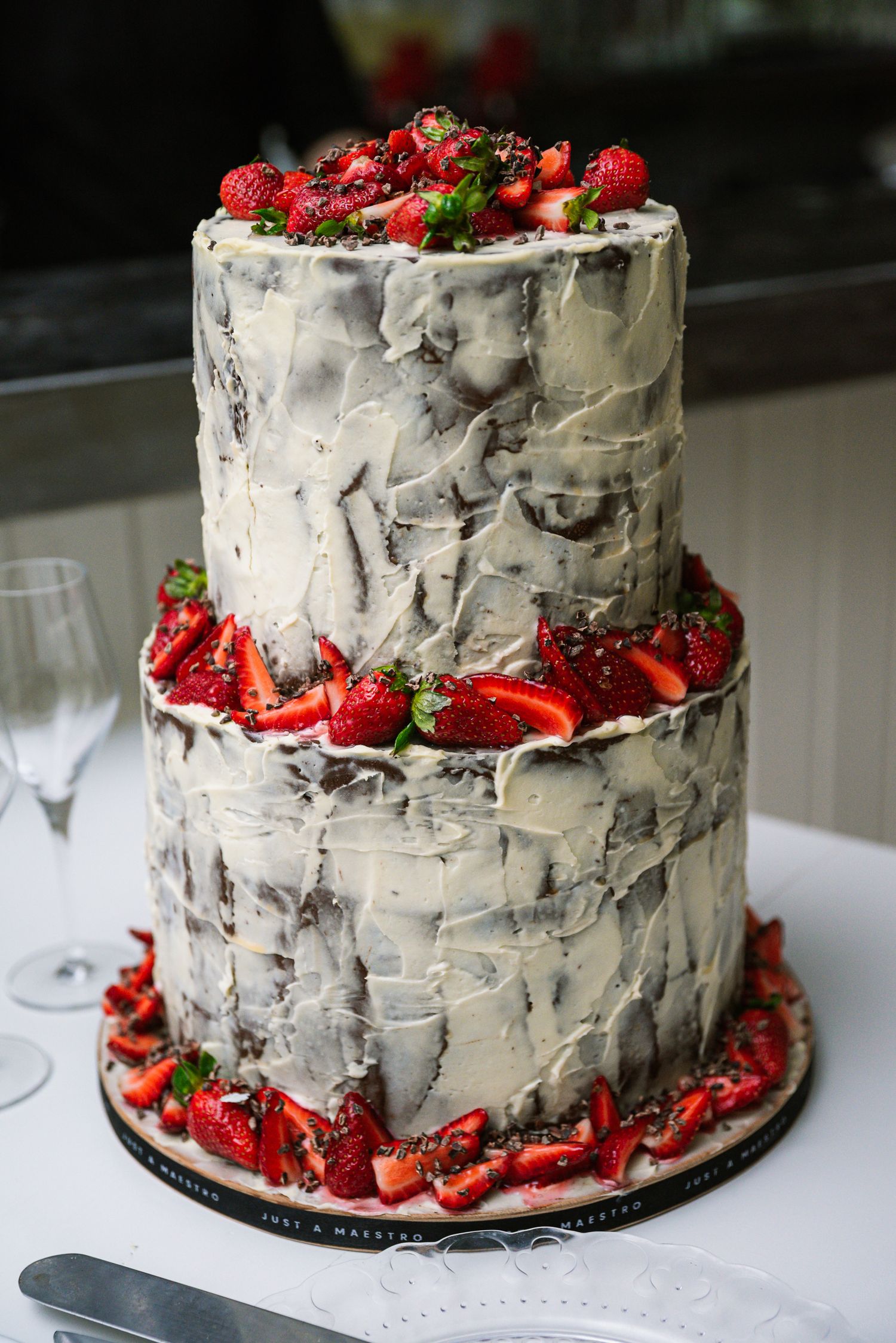 Elegant two-tier white wedding cake decorated with fresh strawberries and raspberries.