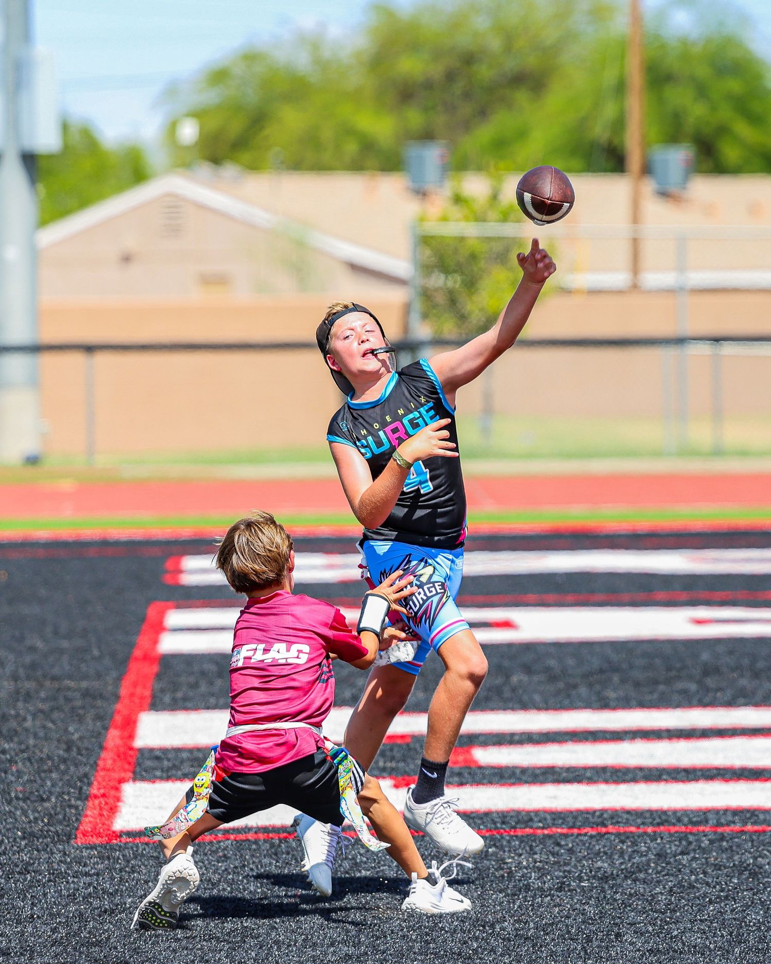 A flag football player leaps high to tip the ball while a defender attempts to block the pass.