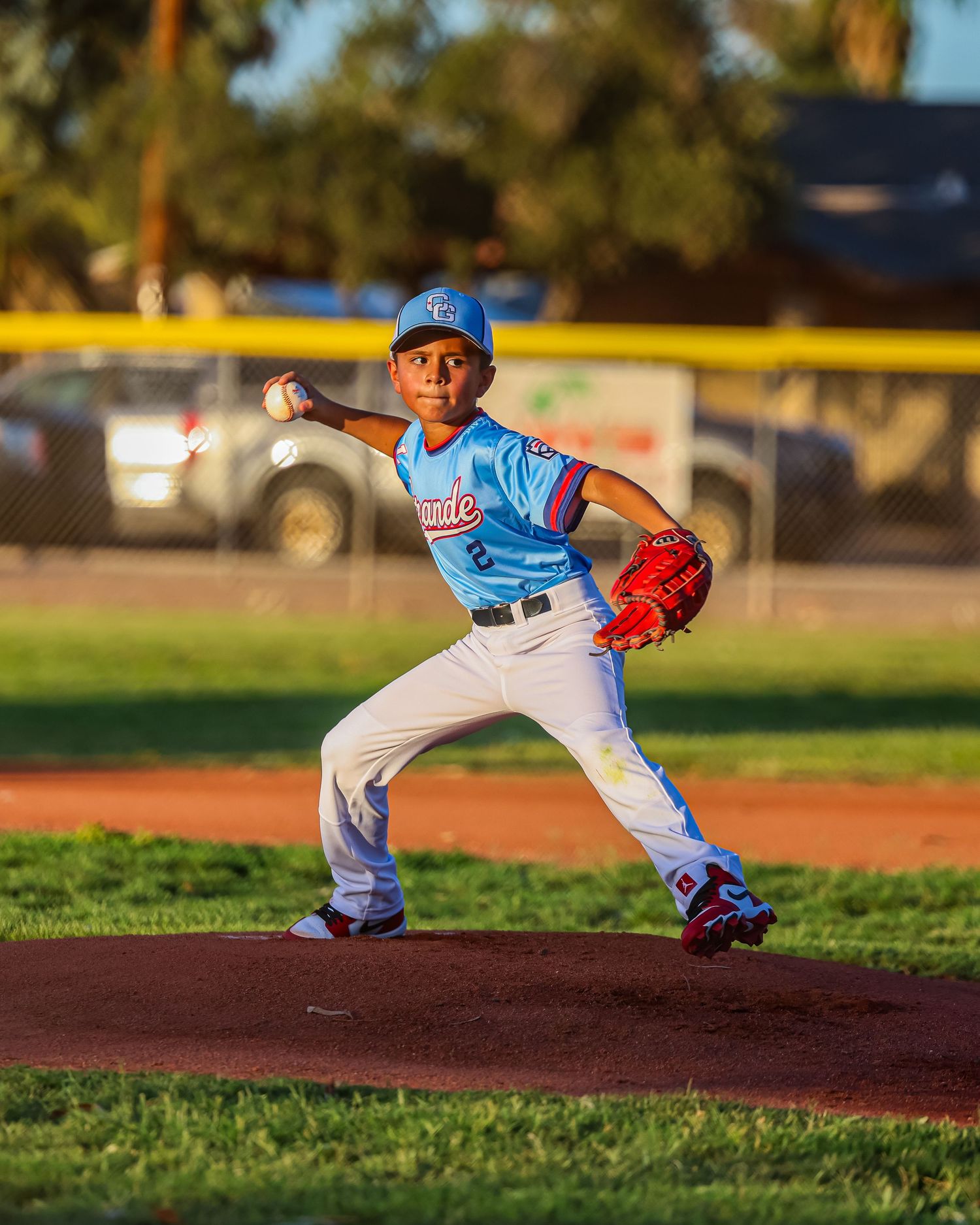 Young baseball pitcher in blue Unite uniform throwing pitch during youth game.