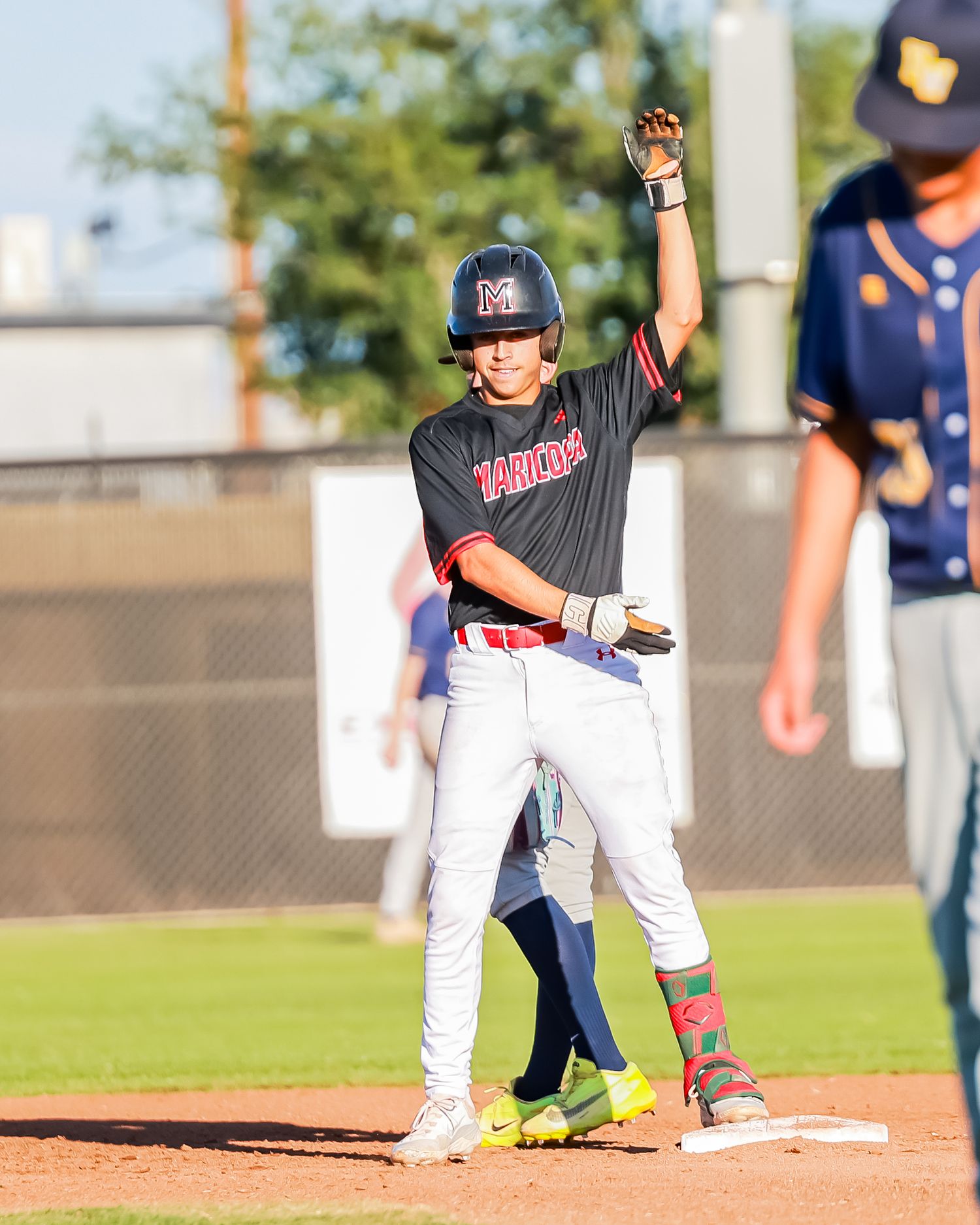 Baseball player in Marlins uniform raises hand triumphantly at base during a game.