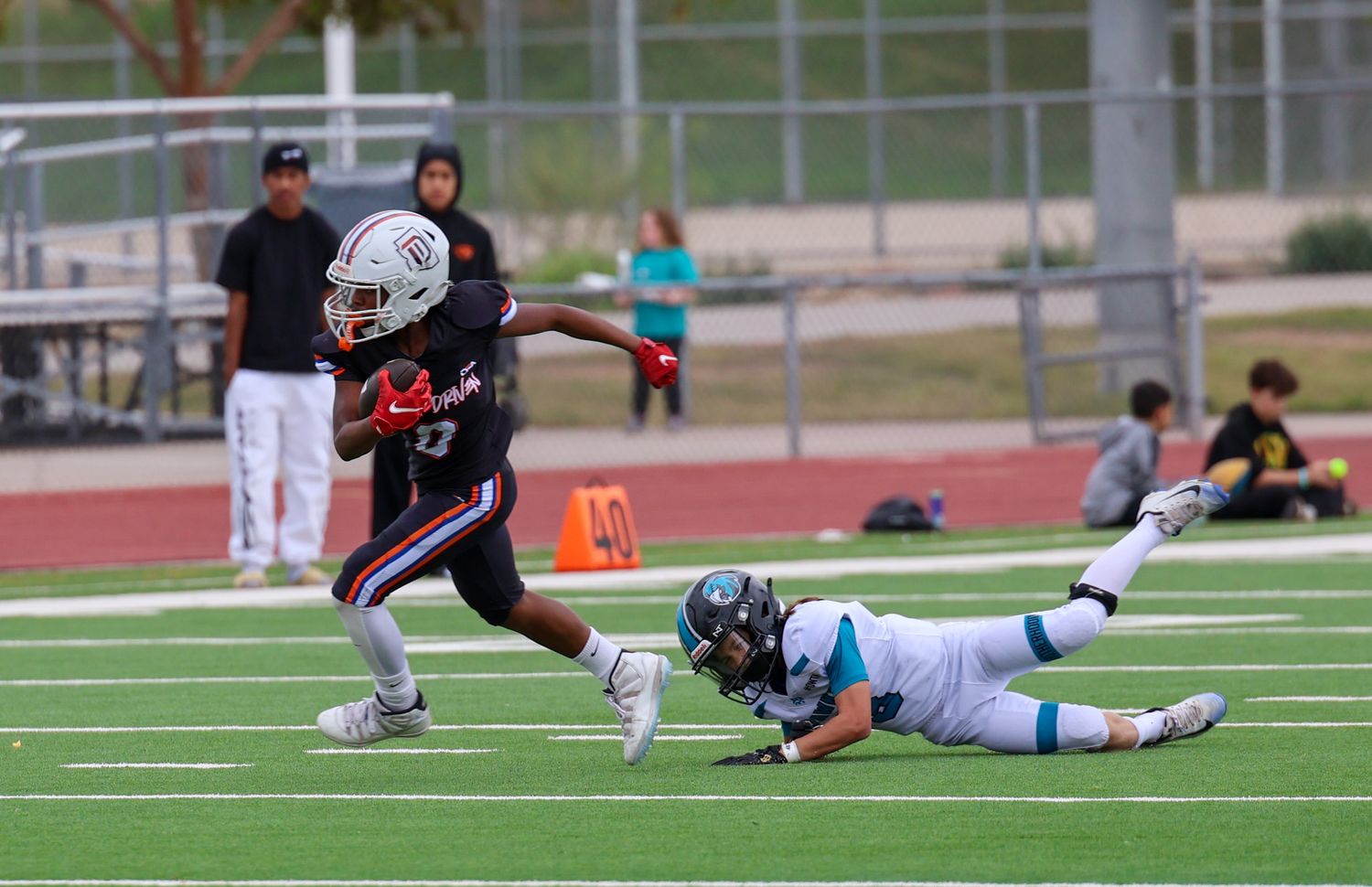 Young football player breaks a tackle attempt during a youth league game on a turf field.