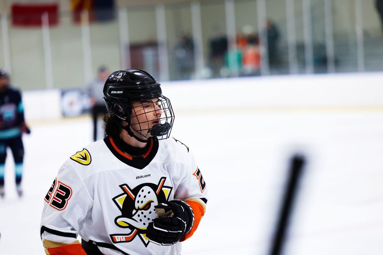 Close-up of ice hockey player in white and orange Anaheim Ducks-style jersey on the rink.