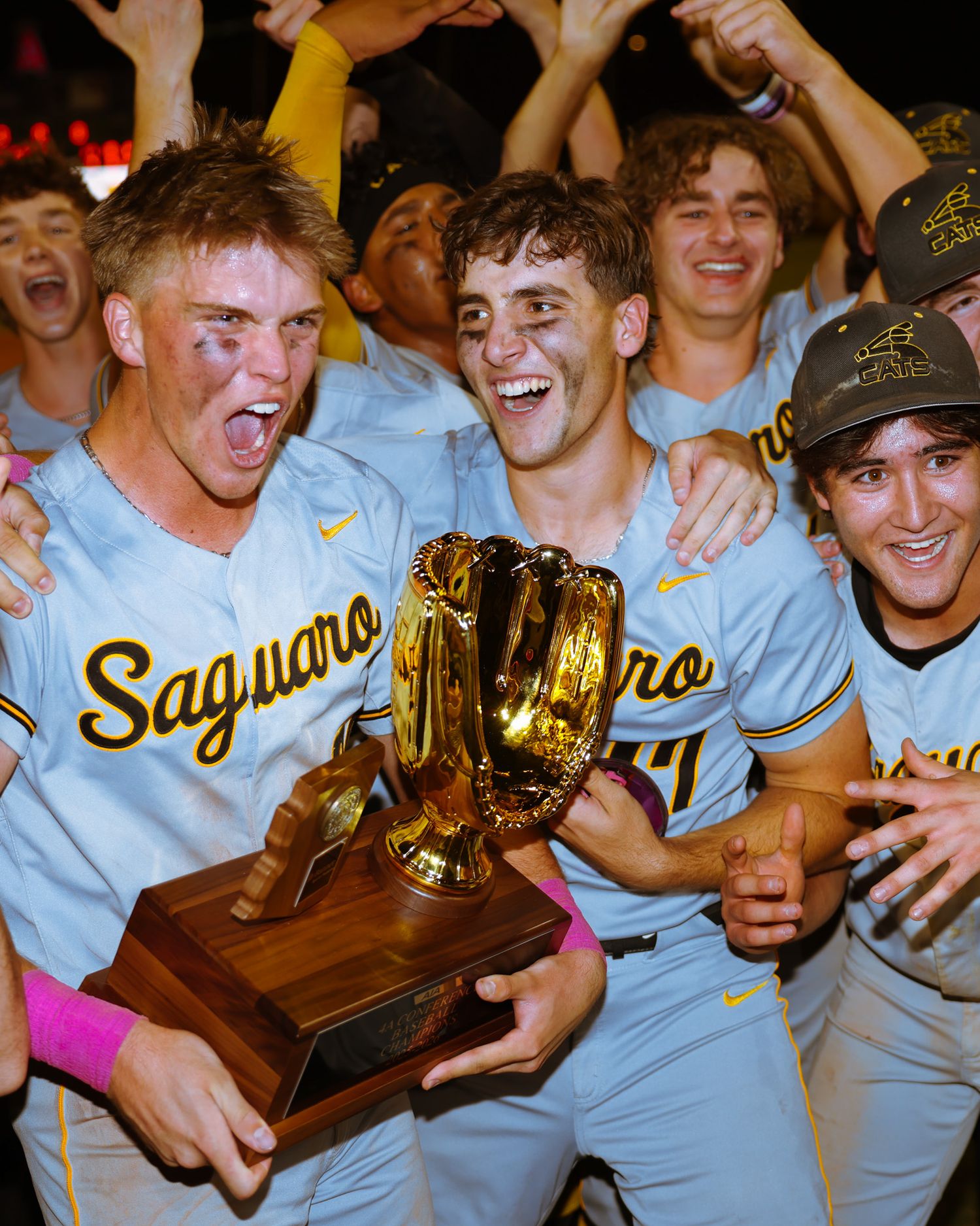 Saguaro baseball players celebrate joyfully while holding golden glove championship trophy.