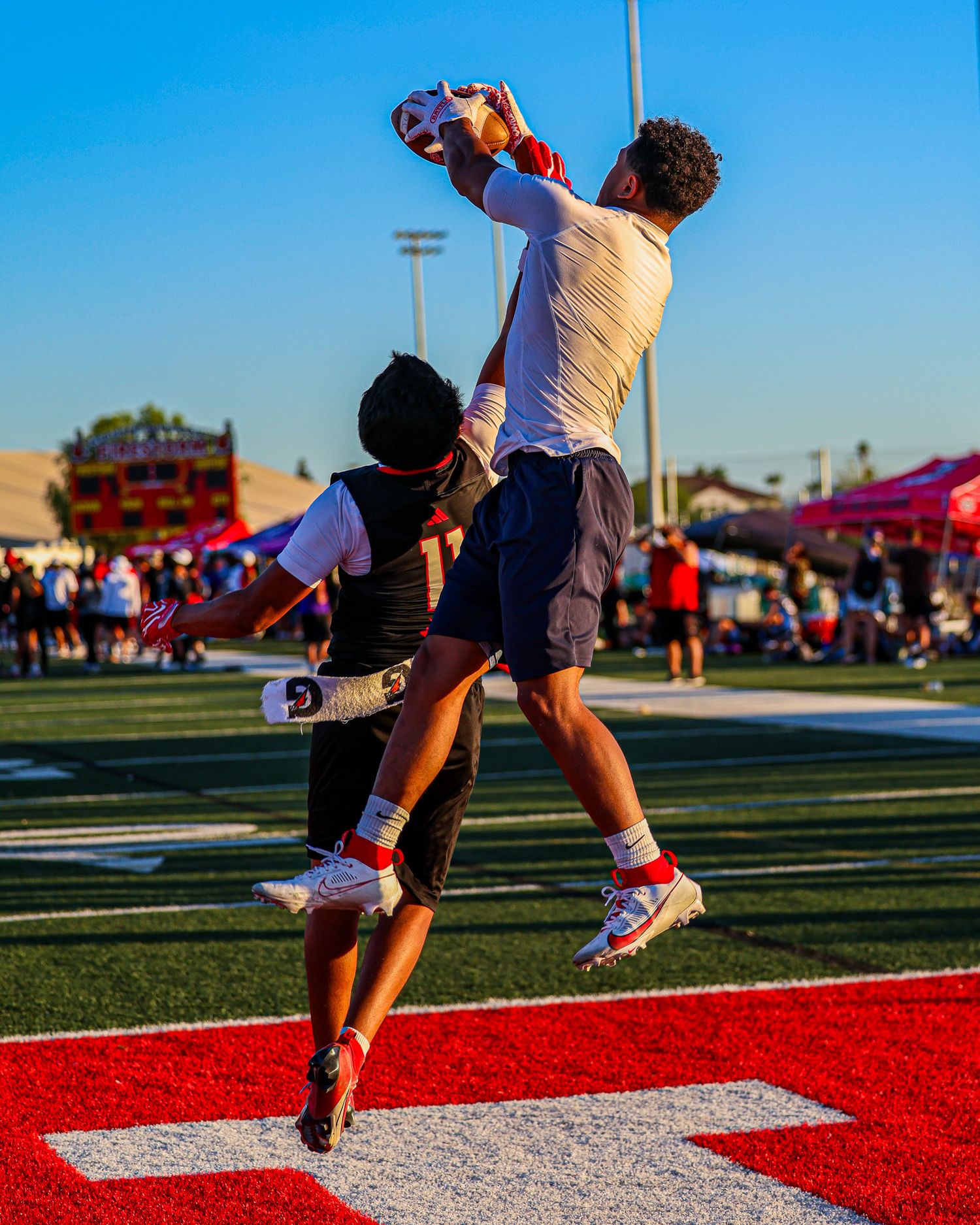 Football player jumps high to catch a pass in the end zone during a flag football game.