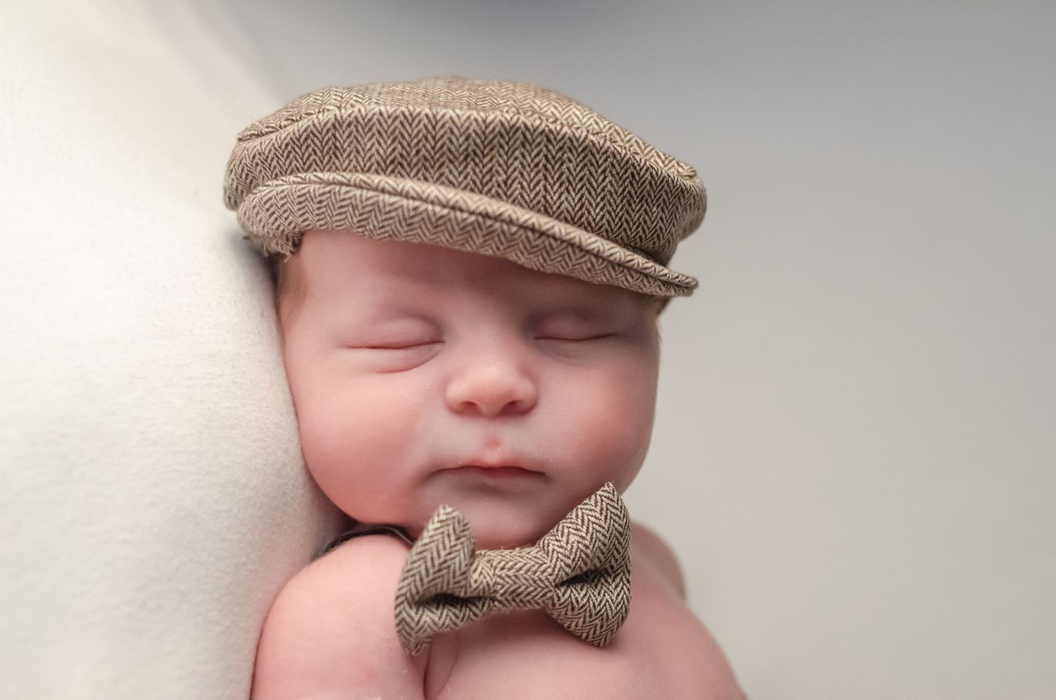 baby boy dressed up with top hat and matching bow tie in newborn photography session
