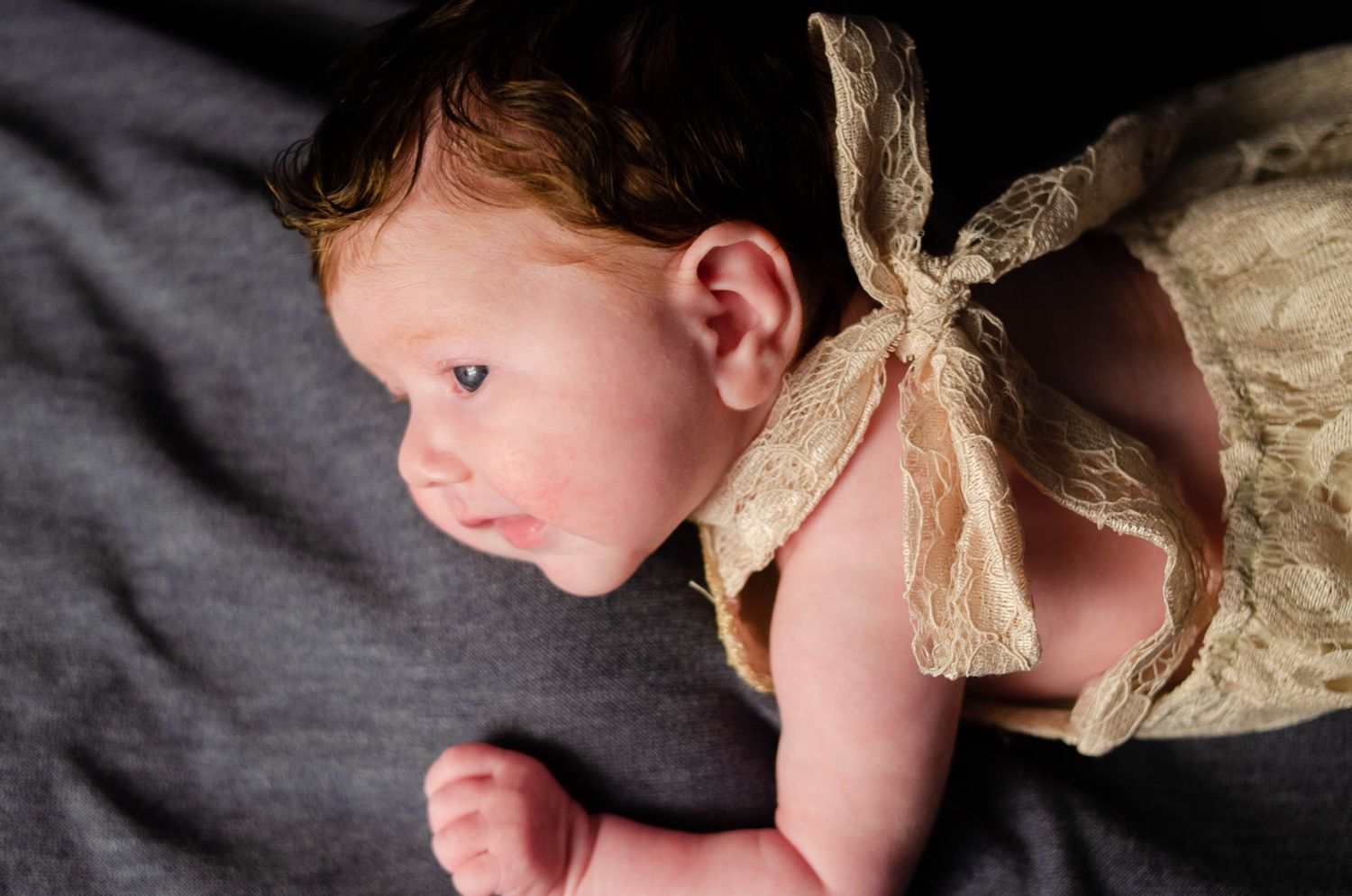 smiling newborn in lace out fit in home newborn photography studio in east texas