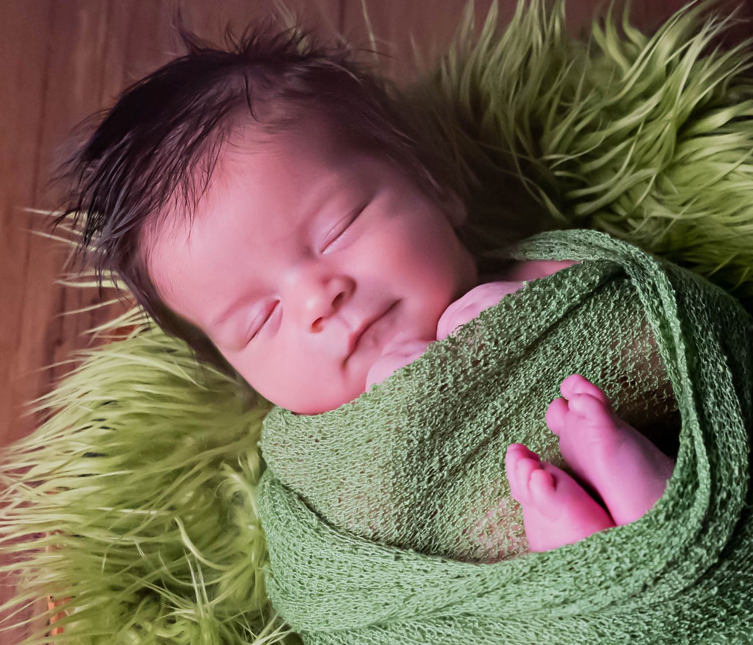 baby boy wrapped in green with fur in newborn portraits in henderson texas