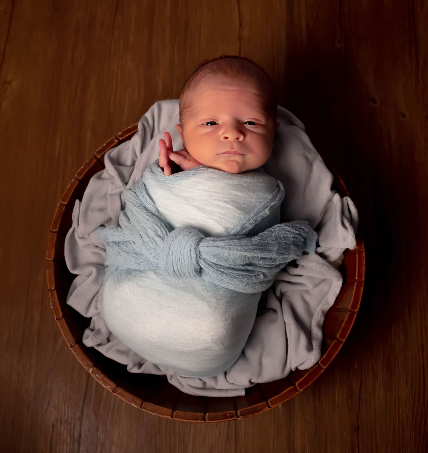Curious boy in blue wrap in brown prop bowl in East Texas Home photography studio