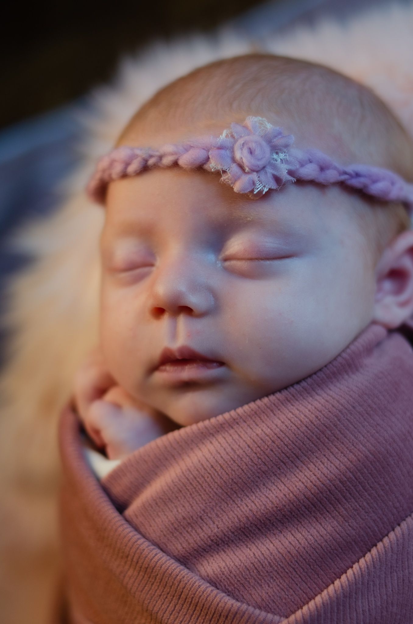 smiling baby girl wrapped in pink cashmere blanket with pink head bow