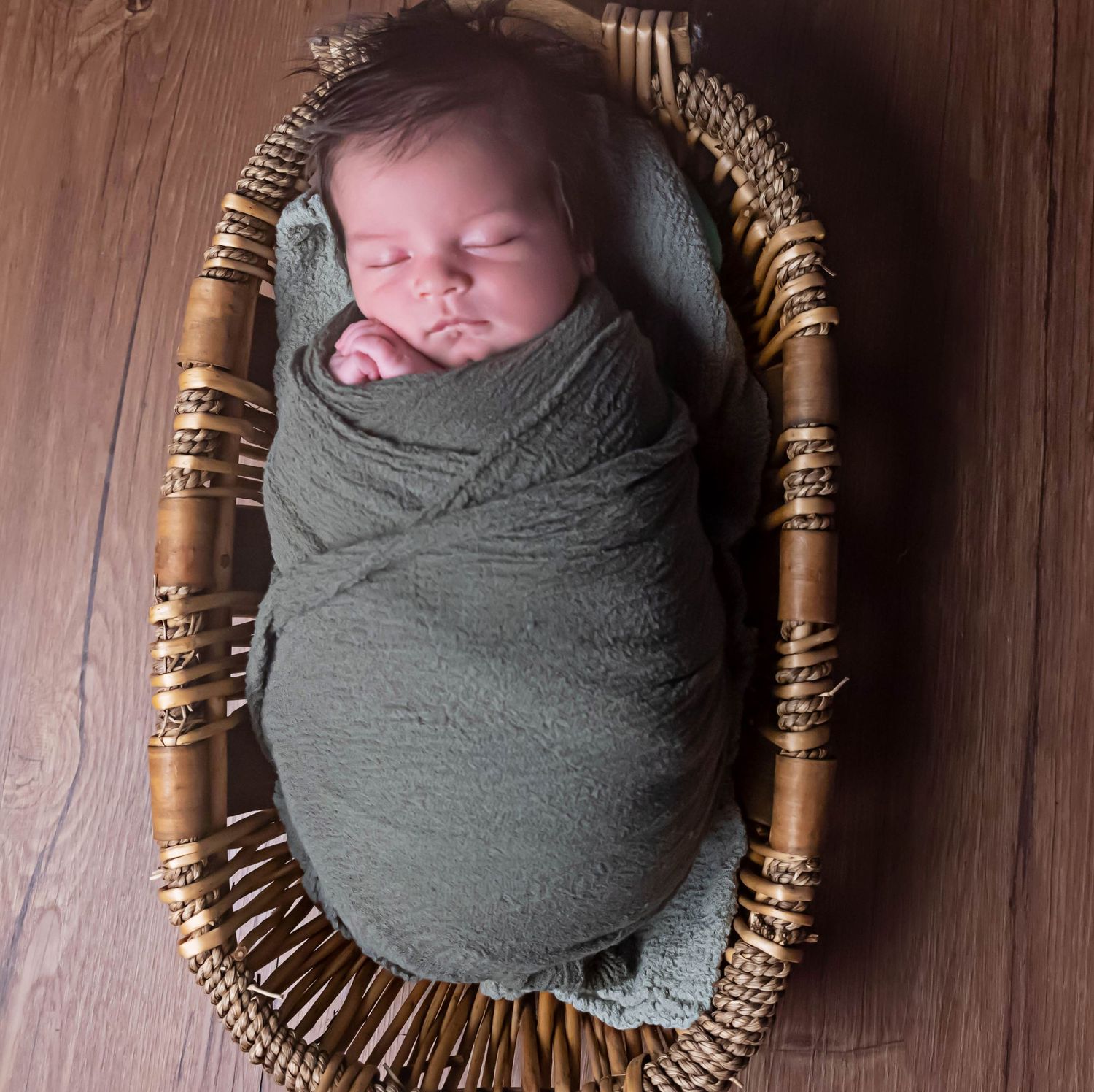 baby boy in wooden bowl like moses wrapped in blanket in home studio