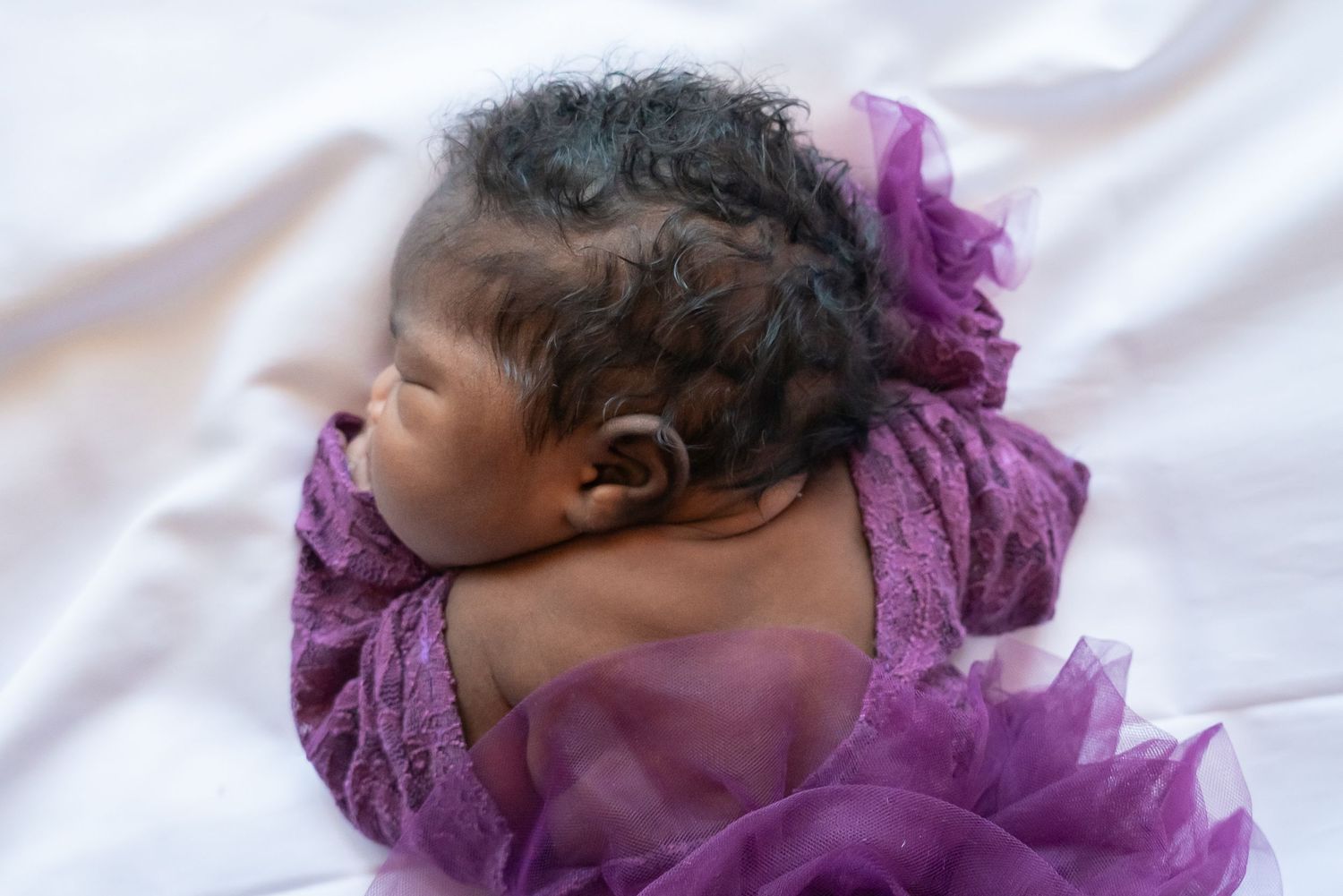 Baby girl in purple dress with black hair in East Texas home photography studio
