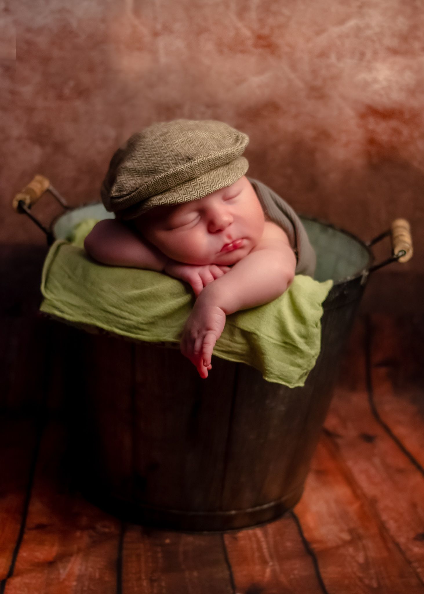 professional portrait of baby boy in mop  bucket prop with brown hat in newborn photography studio