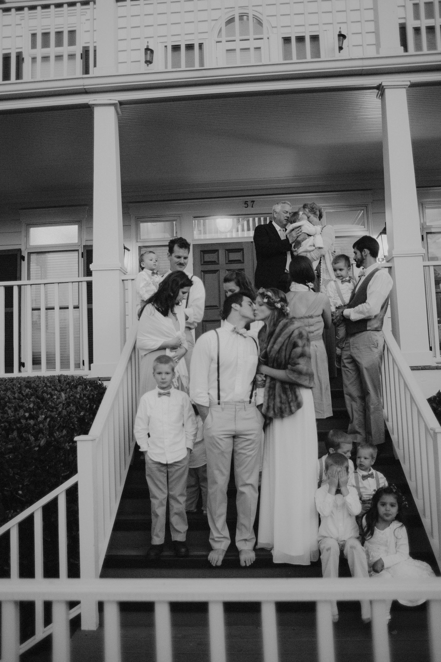 Wedding party gathered on historic home staircase in black and white photo.