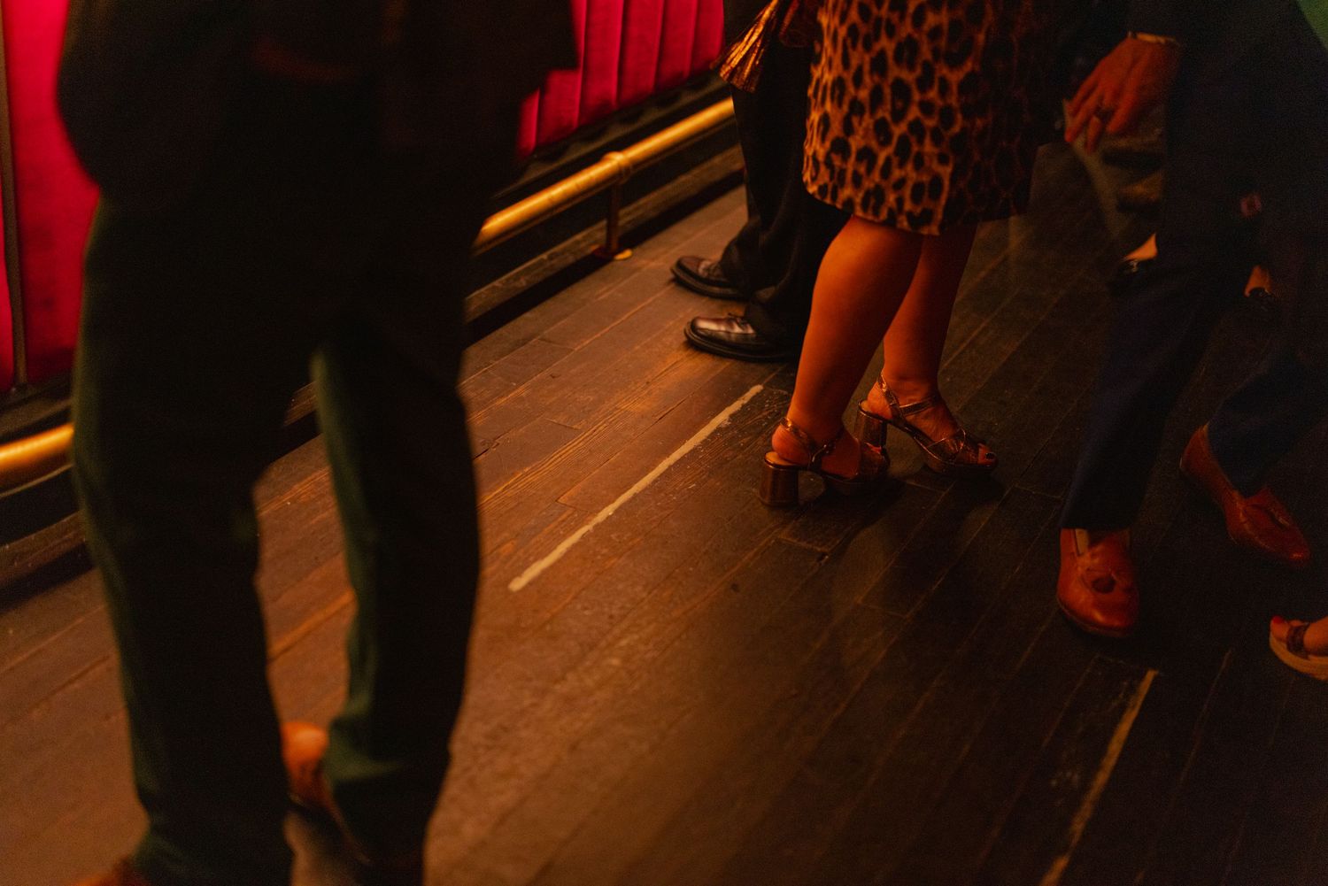 Close-up of guests feet on wooden dance floor at a dimly lit party venue.