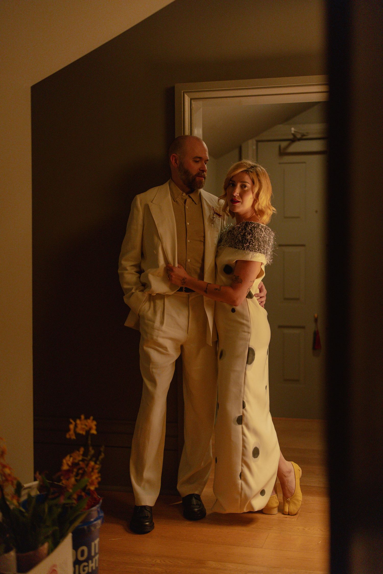 Couple in wedding attire sharing an intimate moment in a warmly lit doorway.
