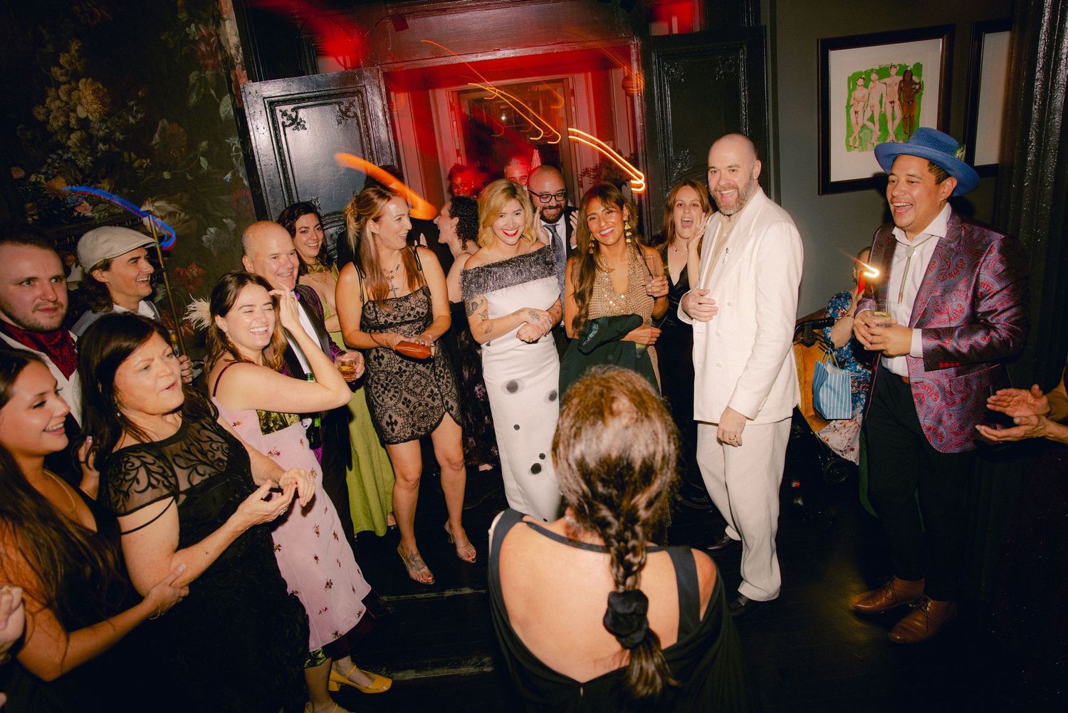 Crowd of elegantly dressed guests gathered around couple at a festive party celebration.