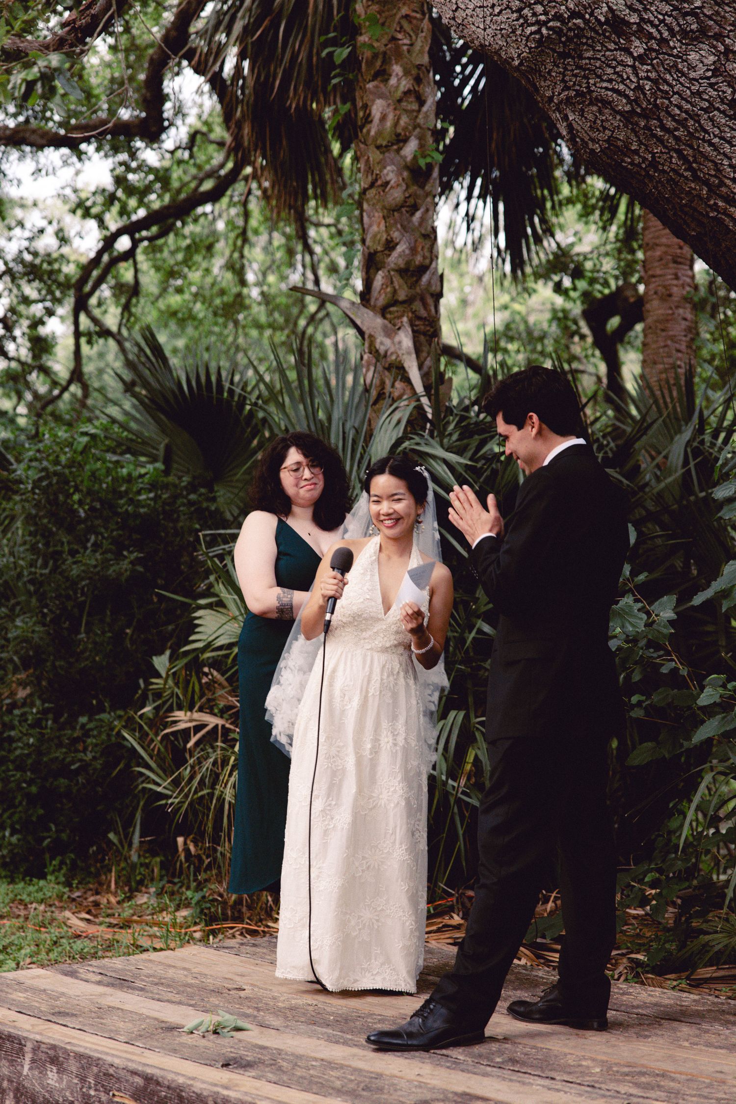 Bride and groom exchange vows outdoors during an intimate garden wedding ceremony with lush tropical greenery.