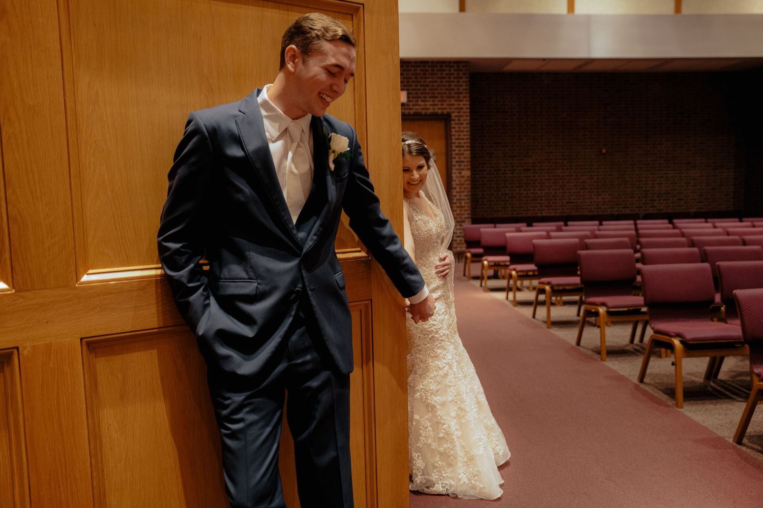 Bride and groom share a tender moment holding hands in a classic church setting.