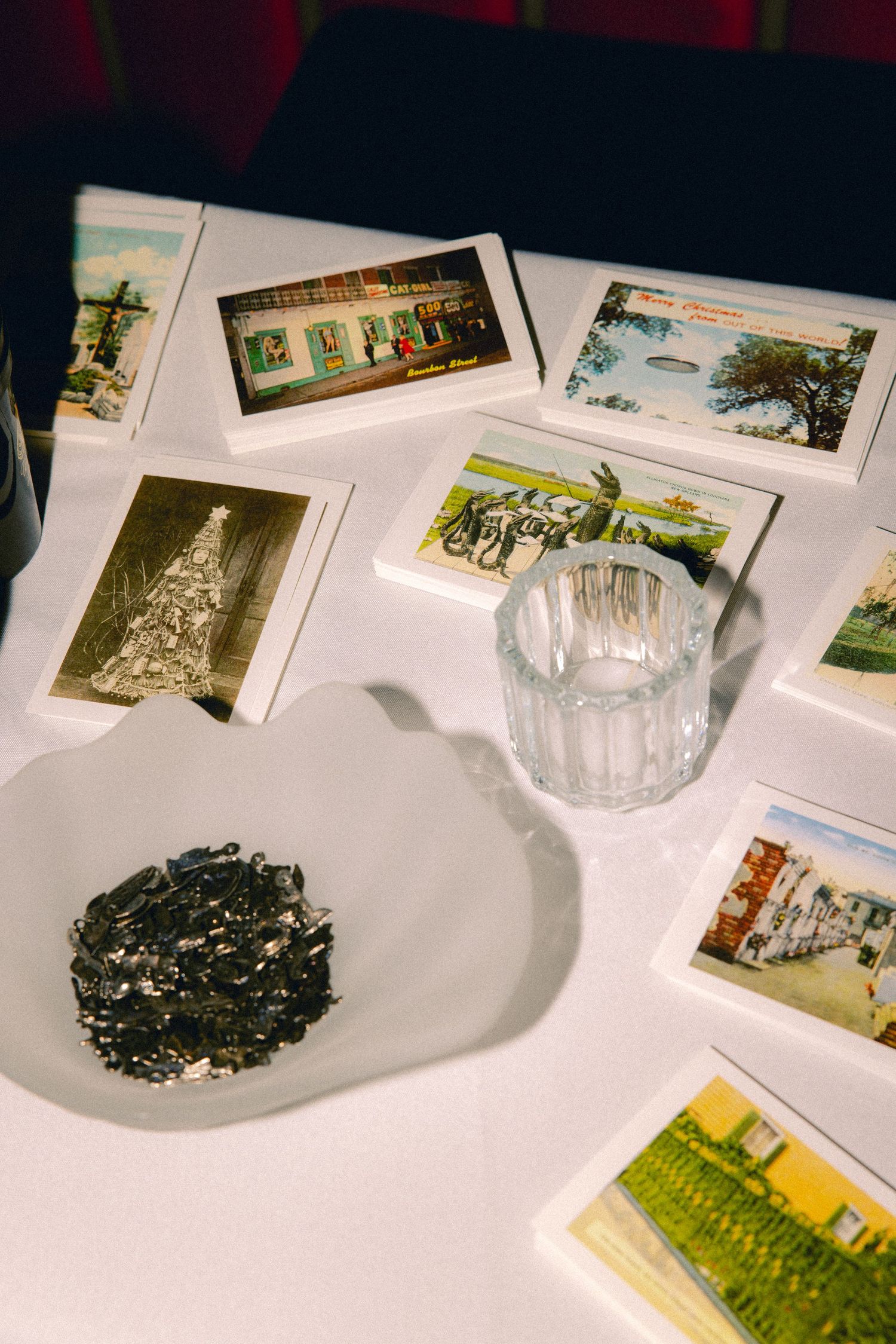 Vintage New Orleans postcards and black confetti scattered on white tablecloth with crystal glass.