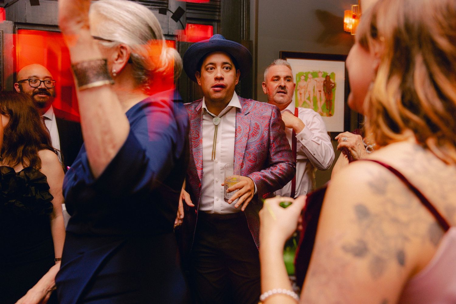 Guests dancing and celebrating in colorful formal attire at a lively indoor party.