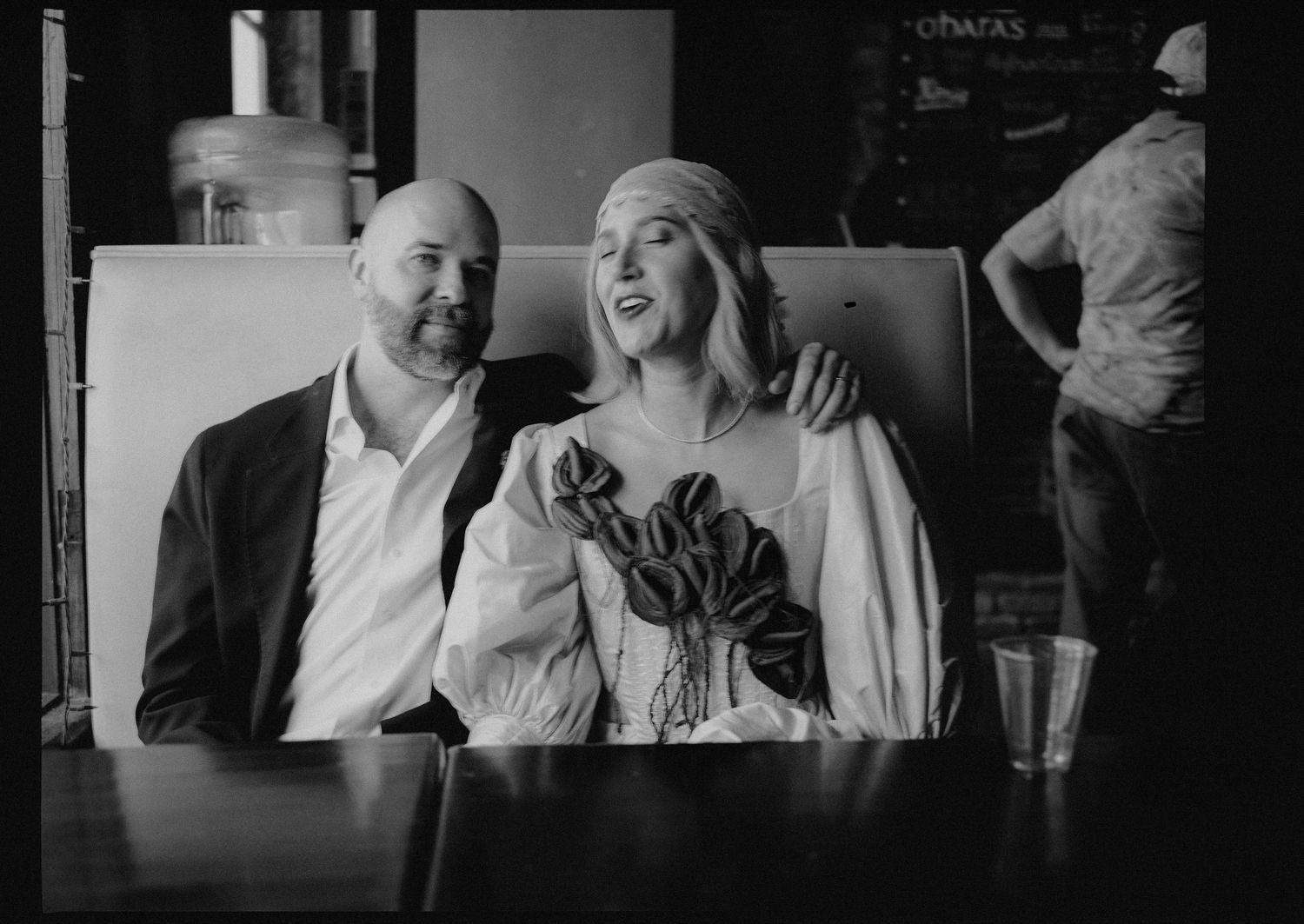 Black and white portrait of smiling bride and groom sitting together at their wedding venue.