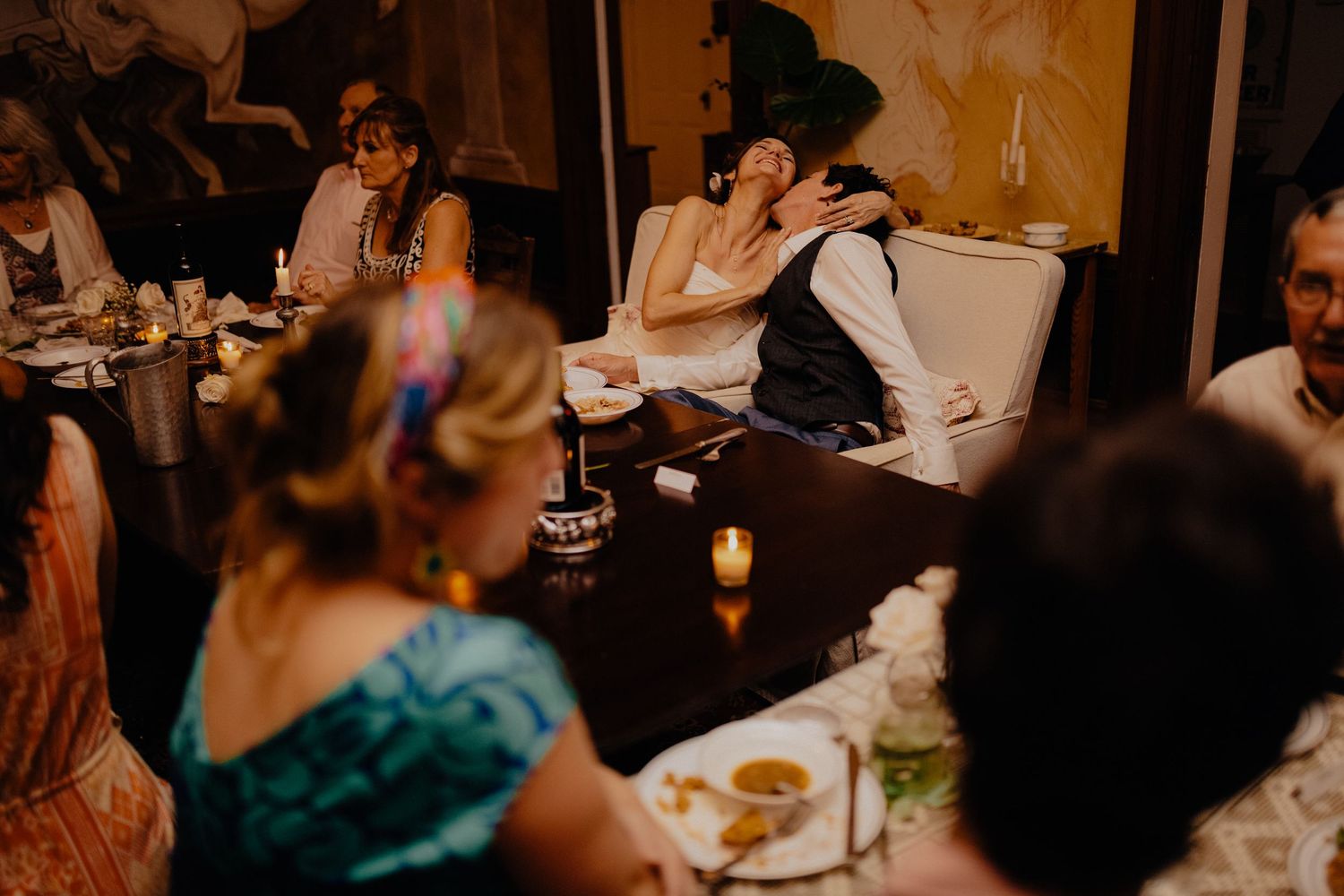Bride and groom sharing a tender embrace at their candlelit wedding reception dinner table.